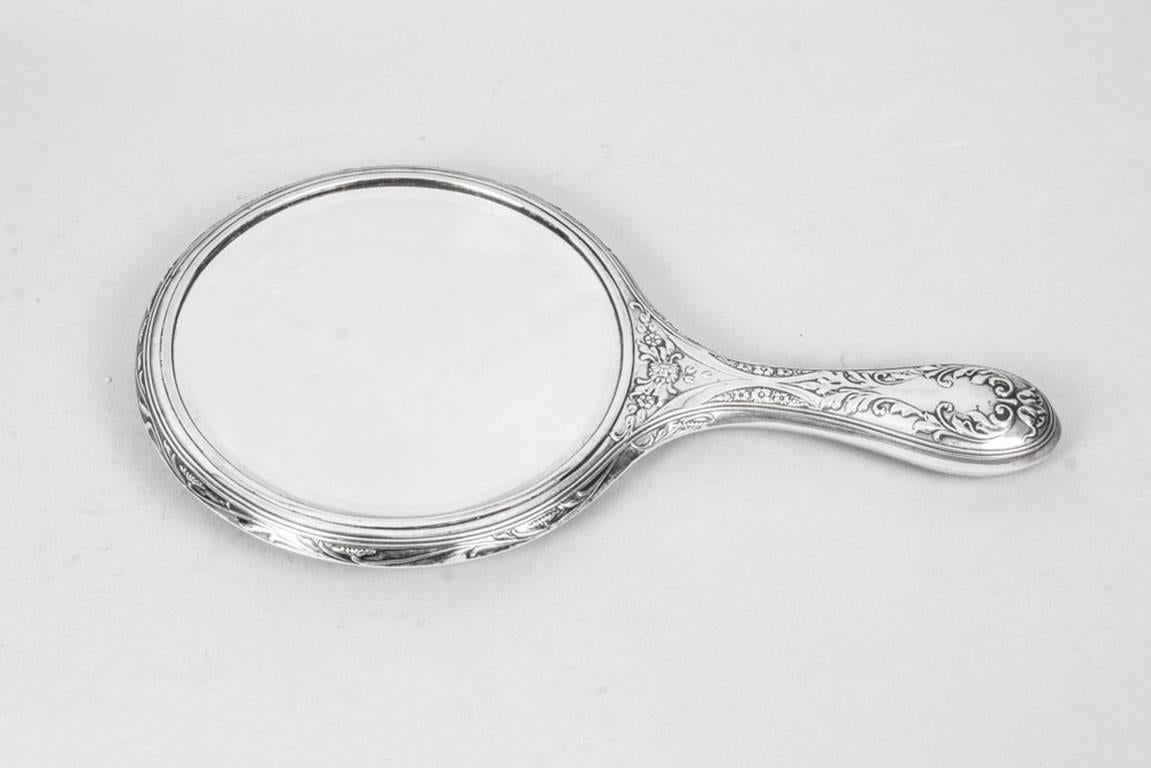 This is a wonderful antique Edwardian sterling silver hand-mirror with hallmarks for Sheffield 1909 and the maker's mark of the renowned silversmiths Walker & Hall.
 
The vanity bevelled mirror features a heavy embossed solid silver decoration in