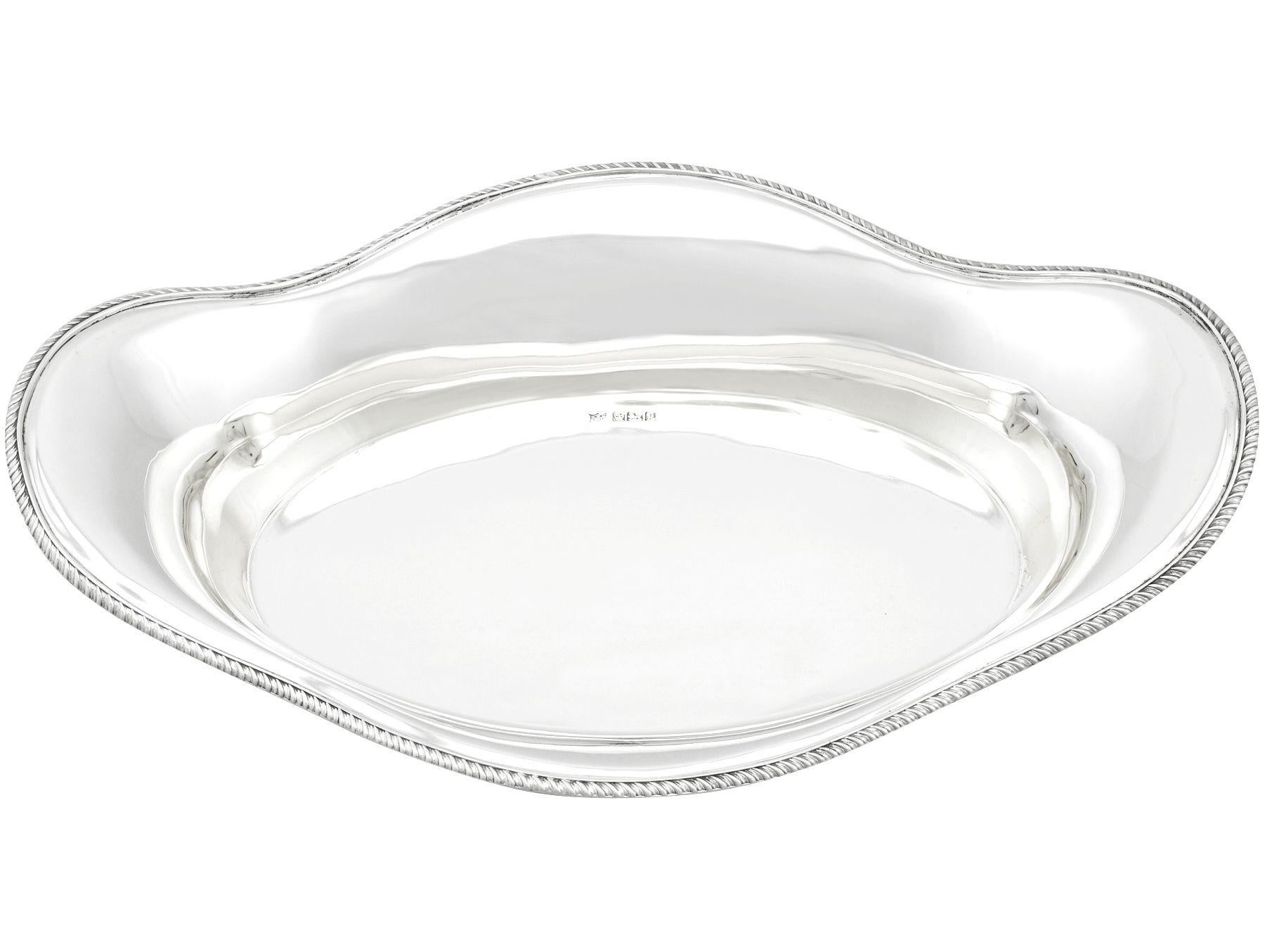 A fine and impressive antique Edwardian English sterling silver bread dish; an addition to our dining silverware collection.

This fine antique sterling silver bread dish has a plain oval boat shaped form.

The flared rim of this Edwardian bread