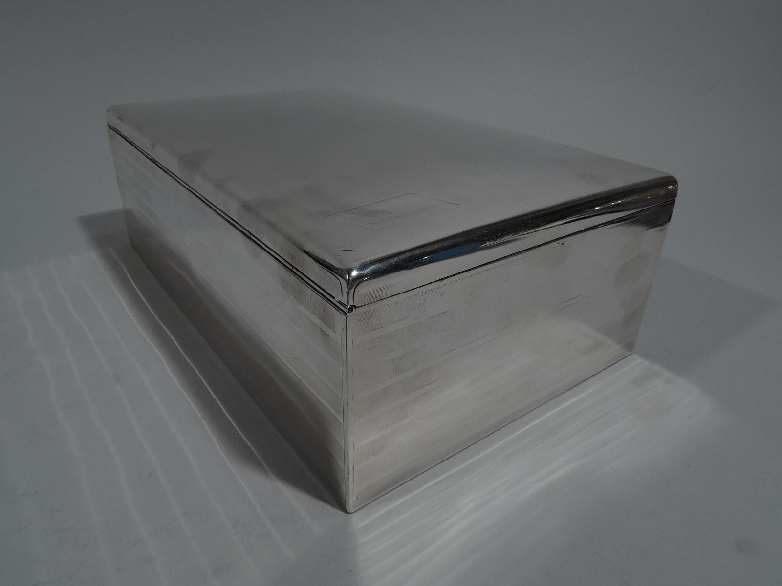 Distinguished Edwardian sterling silver cigar box. Made by Gorham in Providence, ca 1910. Rectangular with straight sides. Cover hinged and gently curved with tab. Wraparound alternating engine-turned lines and plain stripes. Cover same with vacant