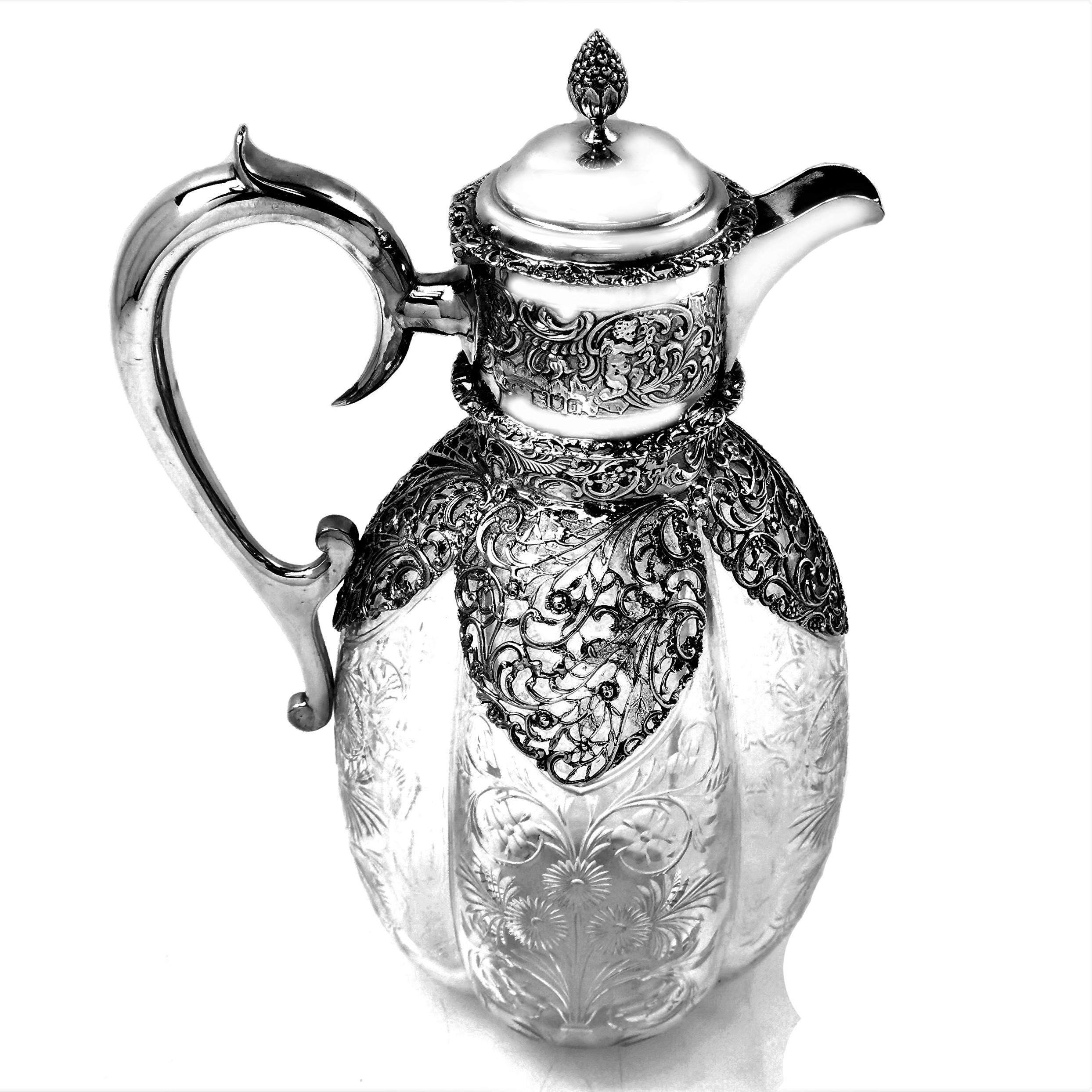 A beautiful Antique Edwardian solid Silver mounted Claret Jug with a cut glass body. The body of the Jug features an elegant quatrefoil shape with each lobe embellished with a delicate floral cut patterns. The Jug has a chased silver neck, lid and