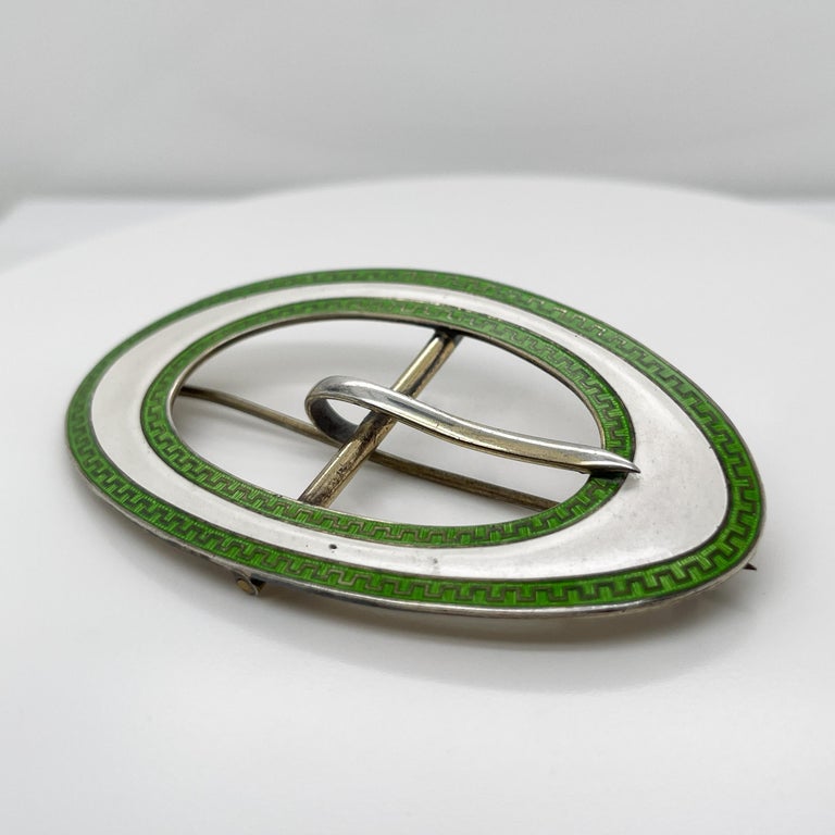 A fine antique sash buckle brooch.

With green and white bands of enamel on a sterling silver frame.

These buckles were de rigueur accessories in the Edwardian period. 

Now converted with a hinged pin and catch to allow it to be worn as a brooch