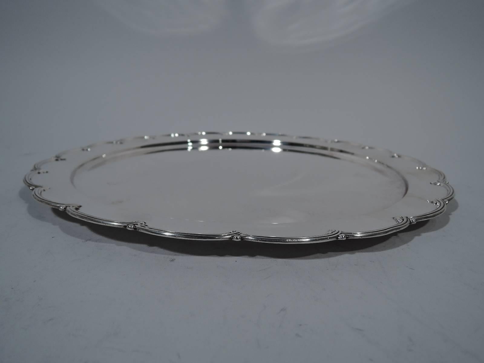 Edwardian sterling silver serving tray. Made by Tiffany & Co. in New York. Circular with well. Petal-scalloped rim with applied reeding. Hallmark includes pattern no. 13562 and director’s letter C (1902-1907). Weight: 19.5 troy ounces.