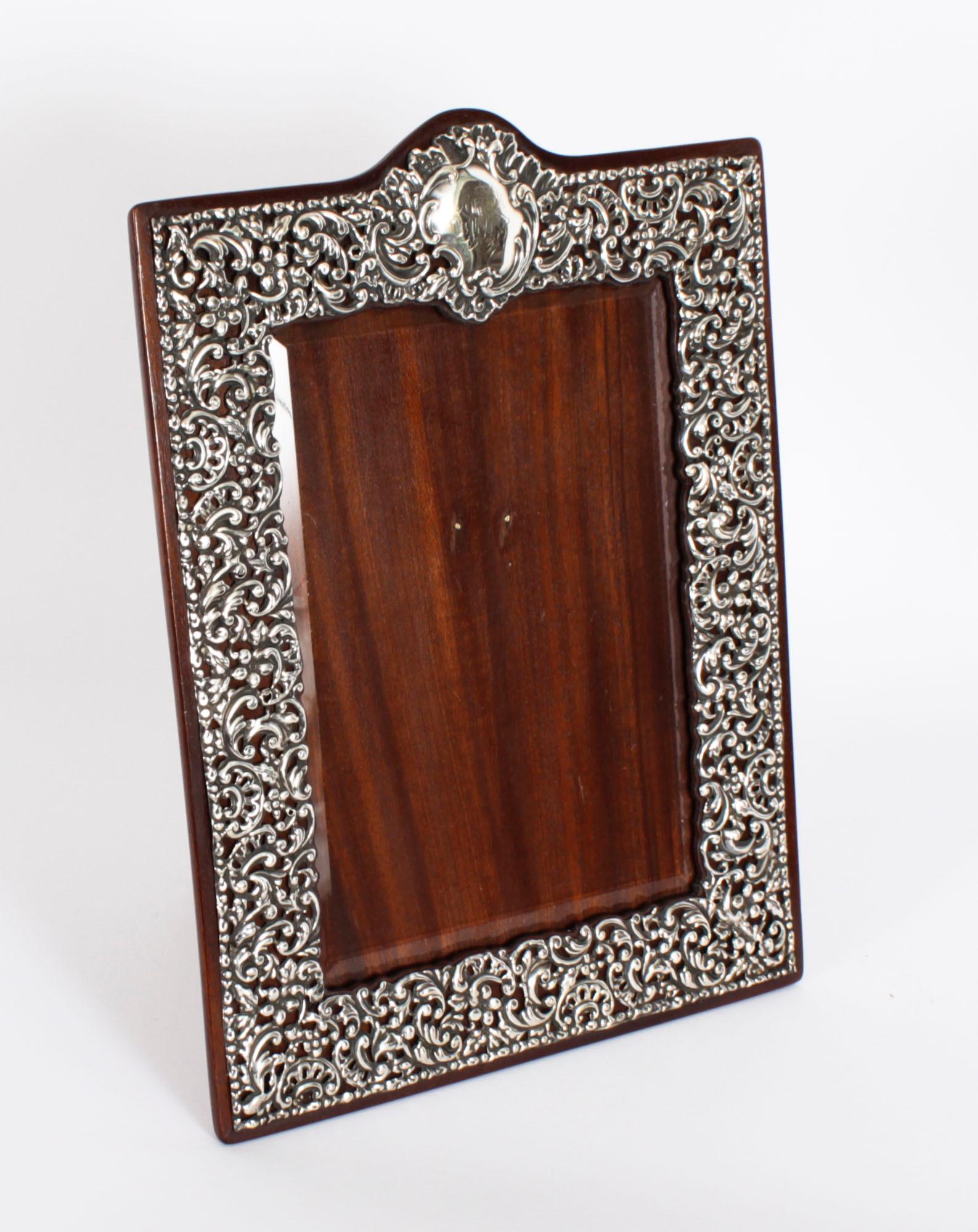 A superb Edwardian sterling silver easel photograph frame with hallmarks for Birmingham 1904.

Beautifully portrait  frame decorated with relief floral, foliate and scroll decoration, having extensive cut decoration, a plain cartouche and a polished