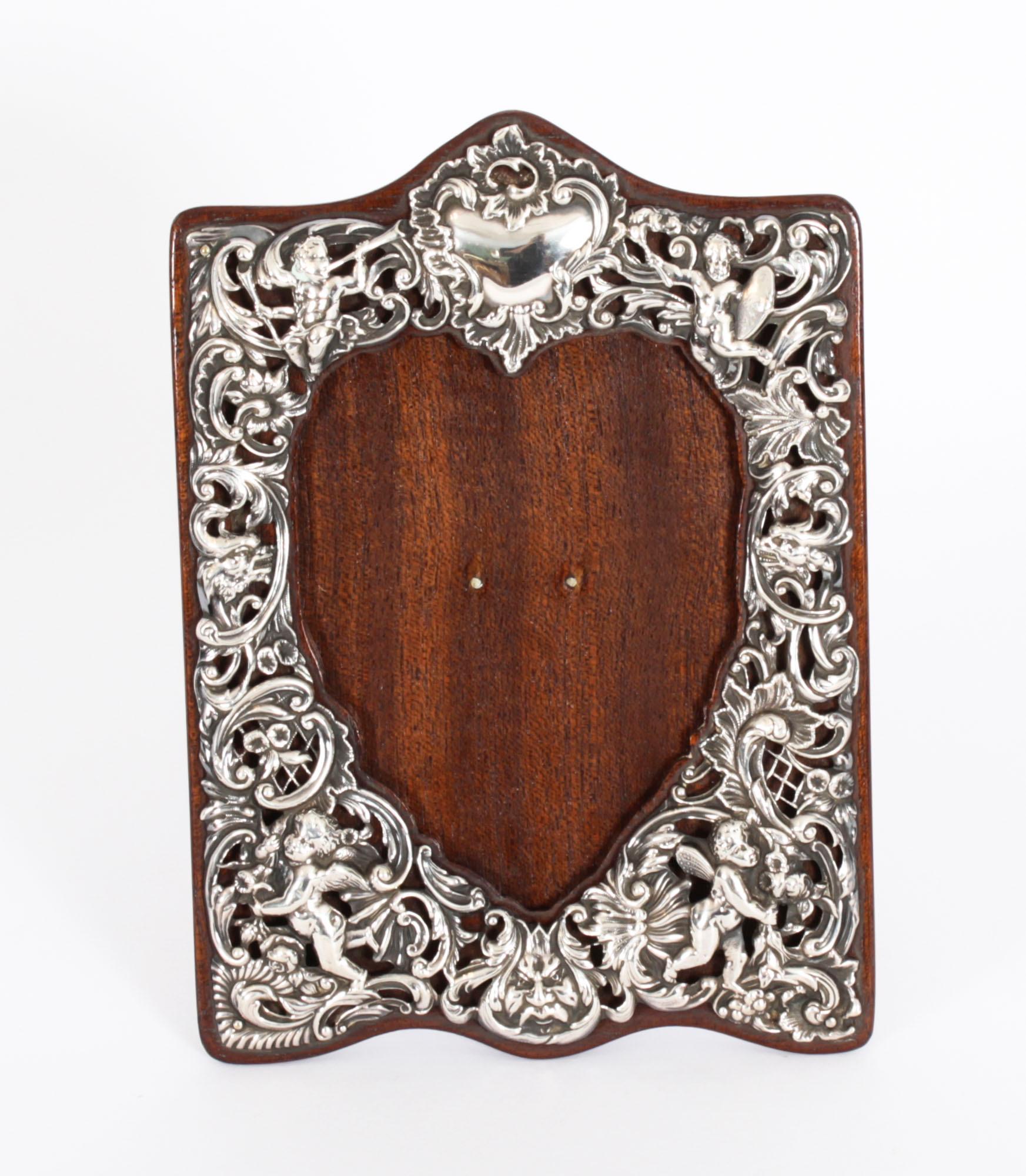 A George V silver easel photograph frame, pierced and embossed with putti amongst frlowers, tellis and leafy scrolls, crested by a vacant cartouche, 19.5cm high, William Comyns, London 1911
Provenance:    Newton Old Hall, Derbyshire

A superb
