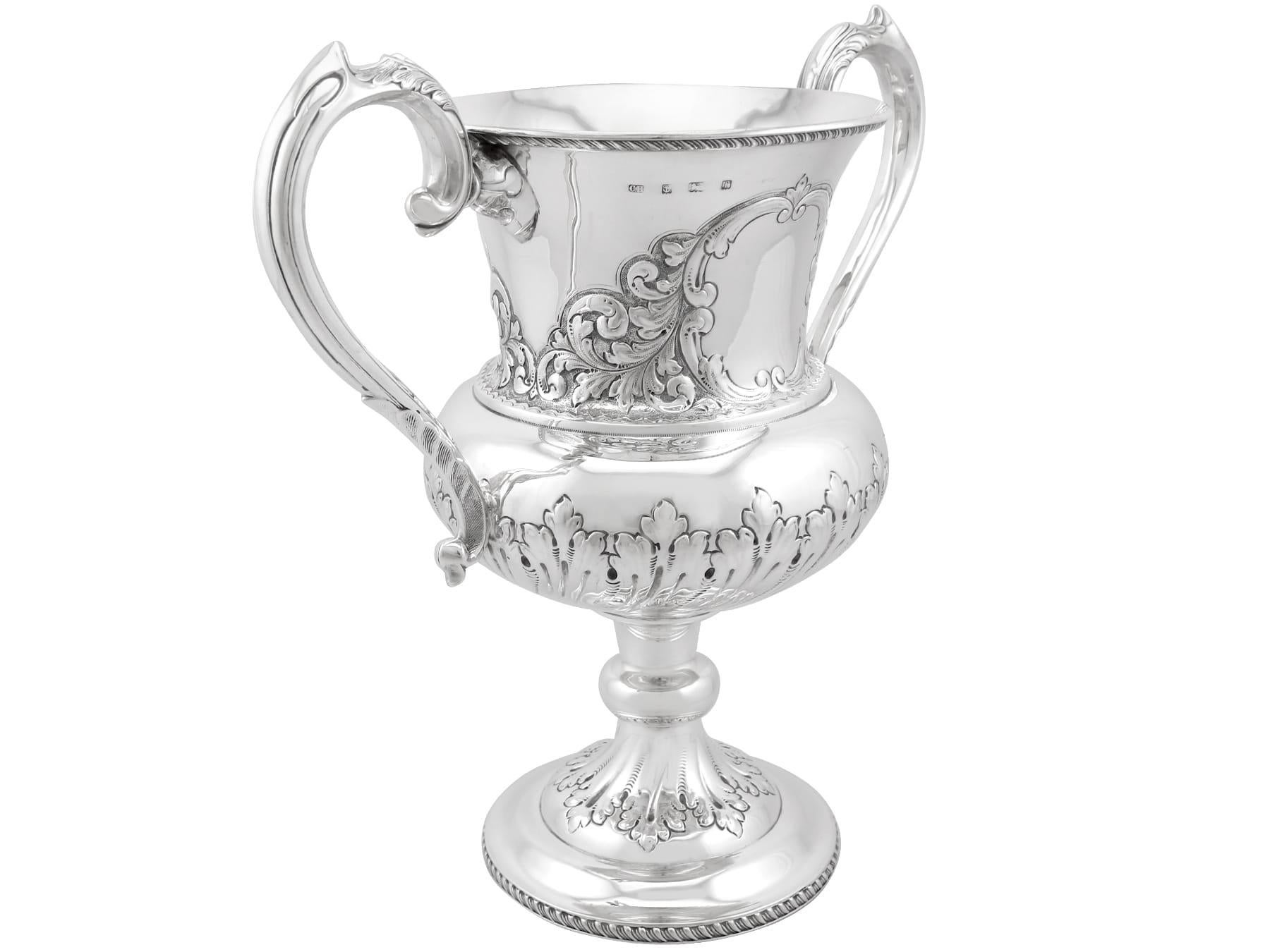An exceptional, fine and impressive antique Edwardian English sterling silver presentation cup; an addition to our presentation silverware collection.

This exceptional Edwardian sterling silver presentation cup has a Campania form onto a knopped