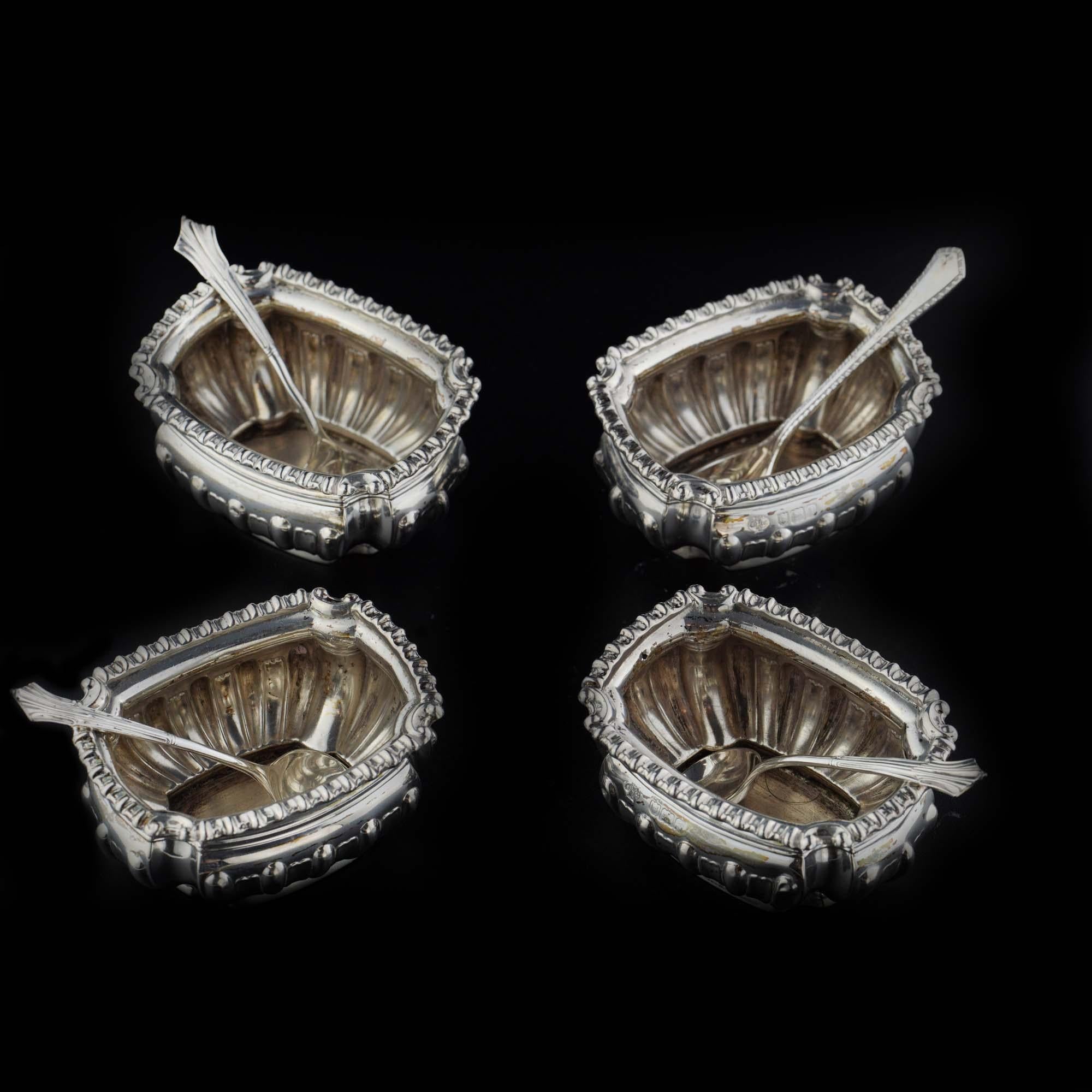 Antique Edwardian sterling silver set of 4 chased salt cellars with spoons. 
Maker: William Hutton & Sons Ltd.
Made in England, London, 1906
Fully hallmarked.

Approx. dimensions :
Length x width x height: 6.5 x 5 x 3 cm 
Total weight: 157