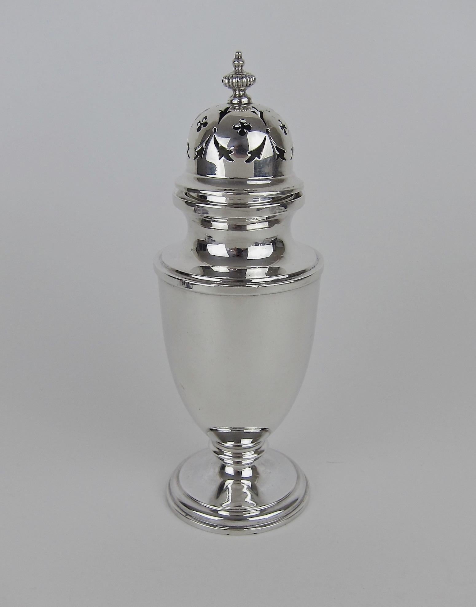 An antique English sugar caster or muffineer made in 1912 by E. S. Barnsley & Co. of Birmingham. The sterling silver sugar shaker has an urn-shaped body on top of a stepped circular foot. The removable dome-shaped cover is pierced with trefid and