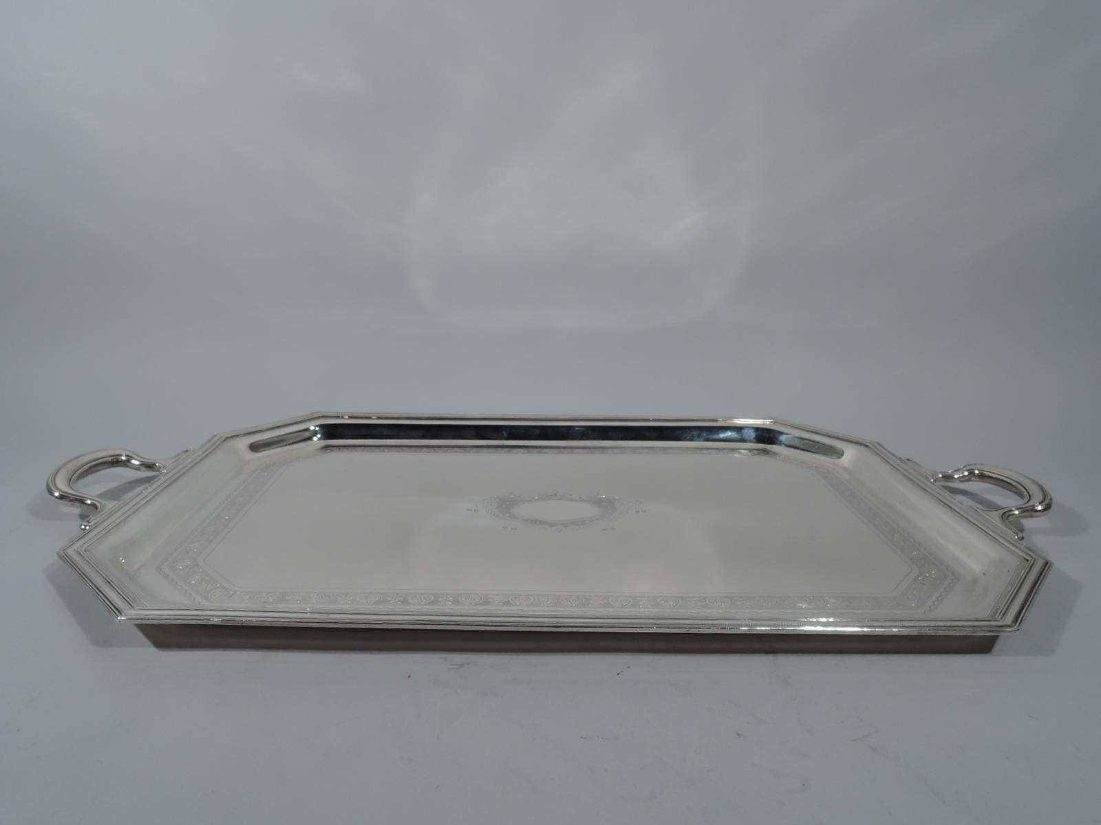 Edwardian sterling silver tea tray. Made by Graff, Washbourne & Dunn in New York. Rectangular with chamfered corners and scroll end handles with sinuous mounts. Molded rim with pointille bands. Well has engraved border with alternating palmettes and
