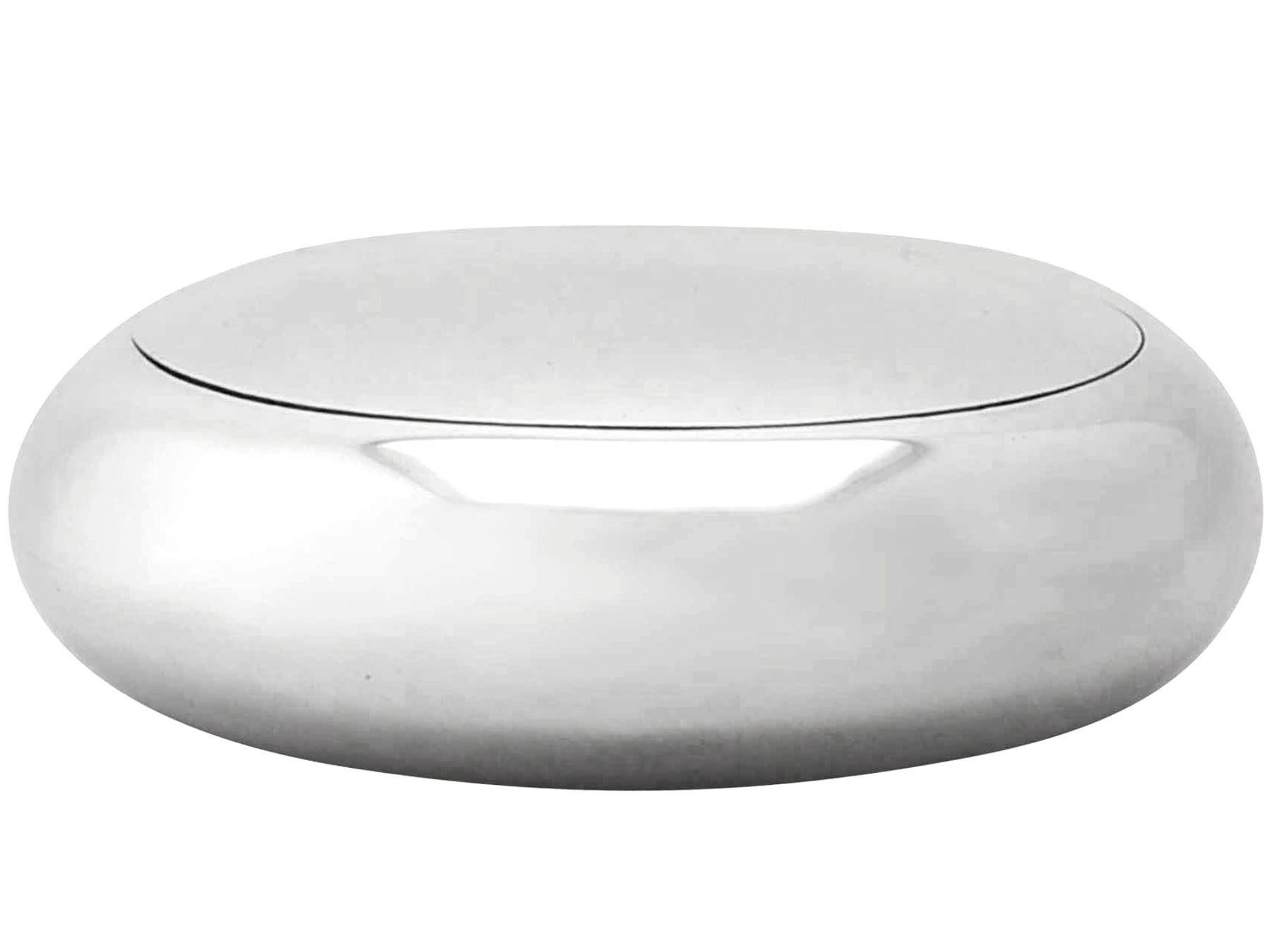 This exceptional antique Edwardian sterling silver tobacco box has a plain circular rounded form.

The underside of this box has a subtly concave form proffering a comfortable fit in the majority of pockets.

The surface of this antique silver