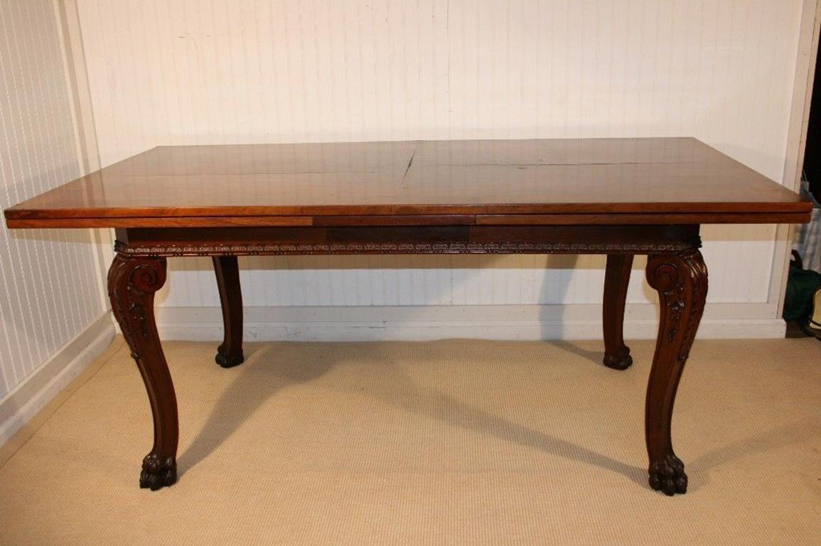 Antique Edwardian style carved walnut extension refectory dining table. Item features finely carved hairy paw feet, carved acanthus knees, banded top, pull-out extensions. Base of table is solid carved wood and top and leaves appear to be a burl