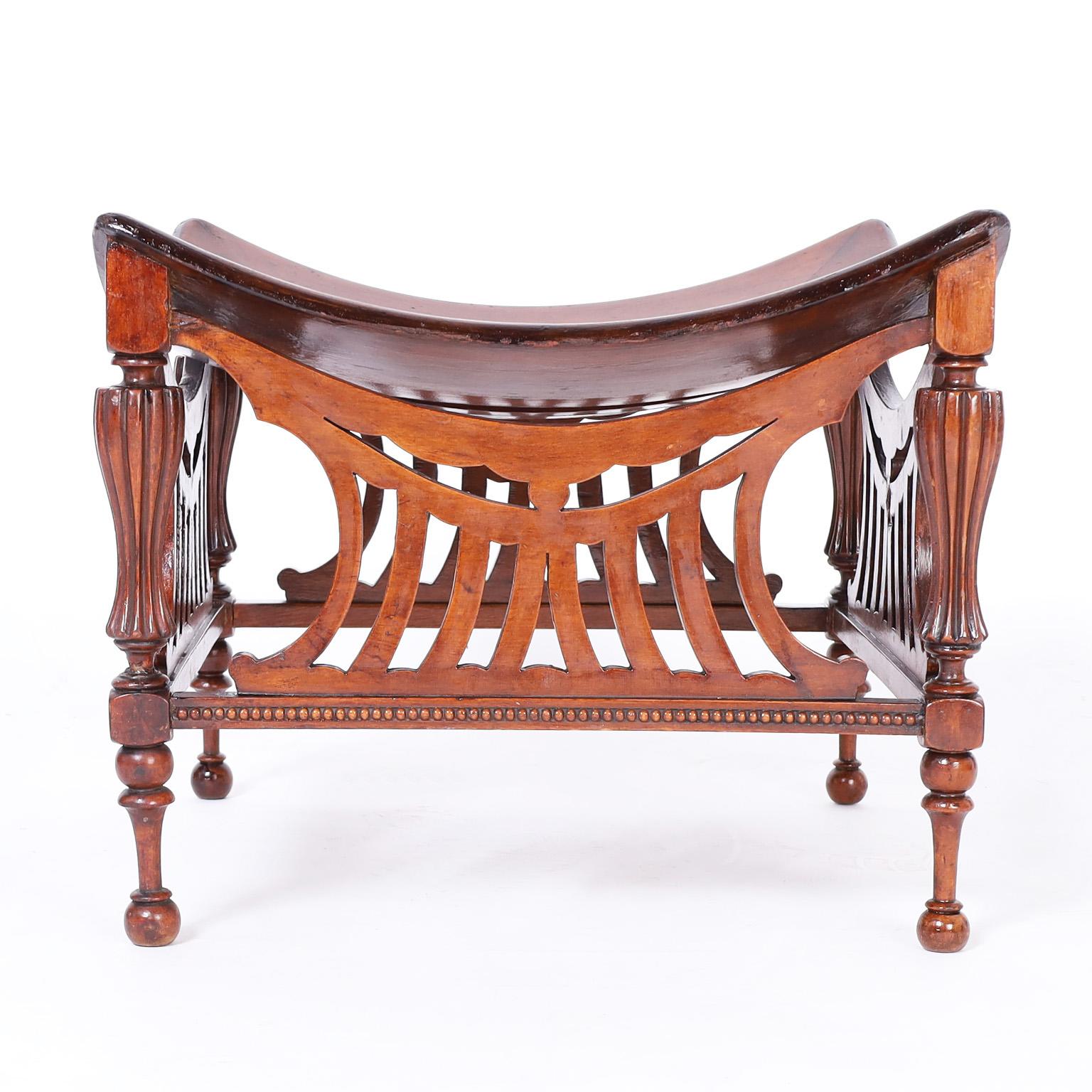 Antique stool crafted in mahogany with an eccentric mix of influences having a Thebes or Egyptian style top over Edwardian stylized side panels and beaded supports on turned legs.