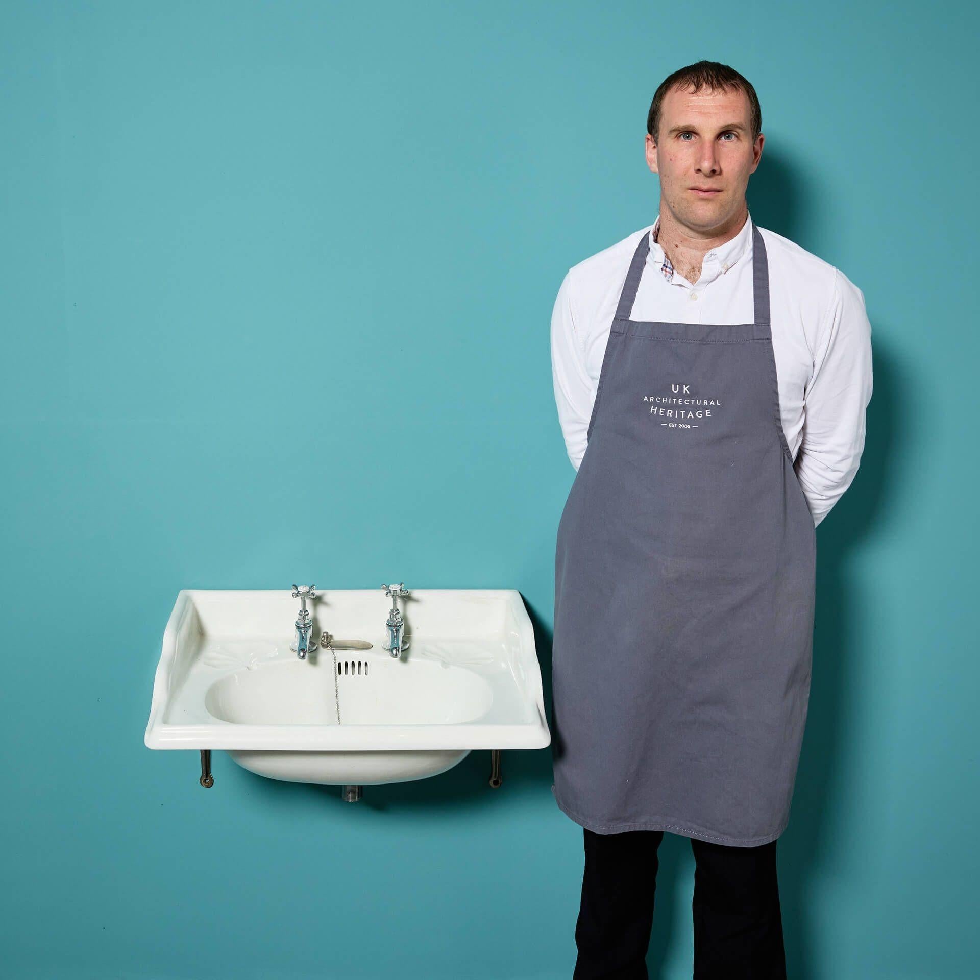 Un évier en céramique classique du début du 20e siècle, de style édouardien antique, avec des robinets modernes de style traditionnel et un support en fonte argentée à fixer au mur. Cette vasque récupérée fera un élégant lavabo dans une salle de