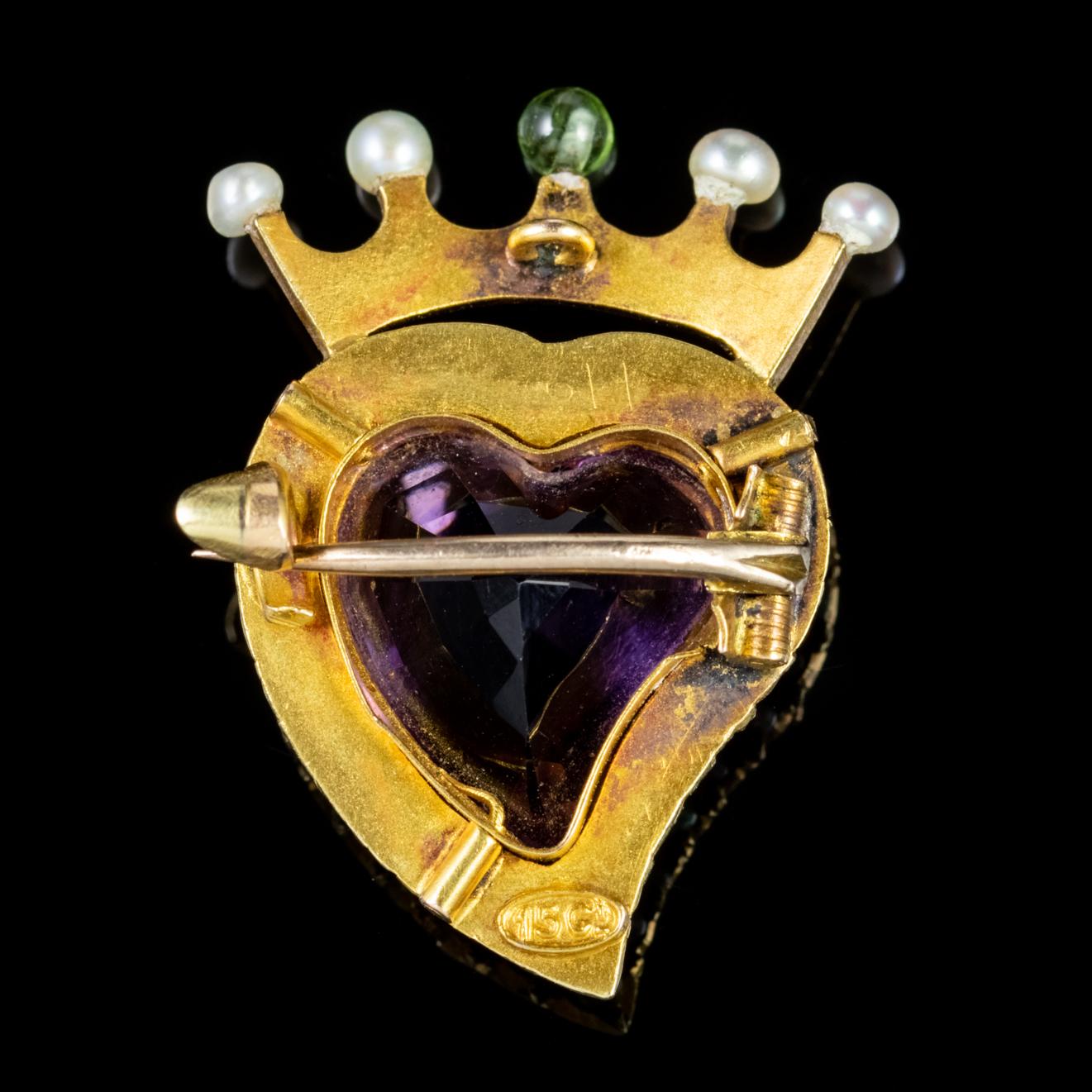 A stunning Edwardian brooch, this piece has been expertly crafted in 15ct Yellow Gold, with a large heart-cut Amethyst at its centre. The heart is ringed with pearls, and each of the points of the crown are tipped with Pearls and a single bright