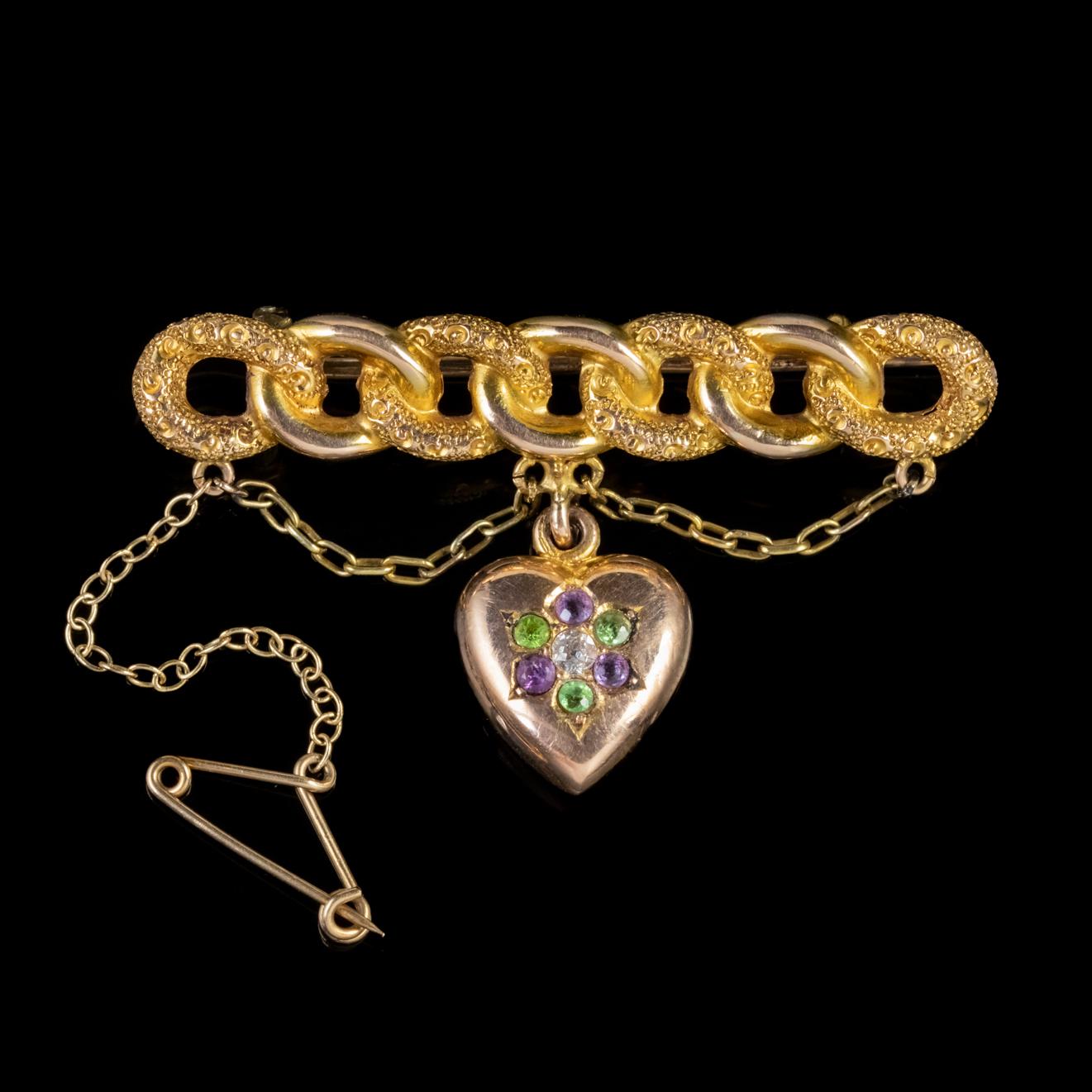 A fabulous Antique Edwardian Suffragette brooch featuring a solid 15ct Yellow Gold chain link gallery with two hanging chains and a lovely Rosy 9ct Gold heart decorated with 0.05ct Peridots, Amethysts and a central 0.08ct Diamond. 

Suffragettes