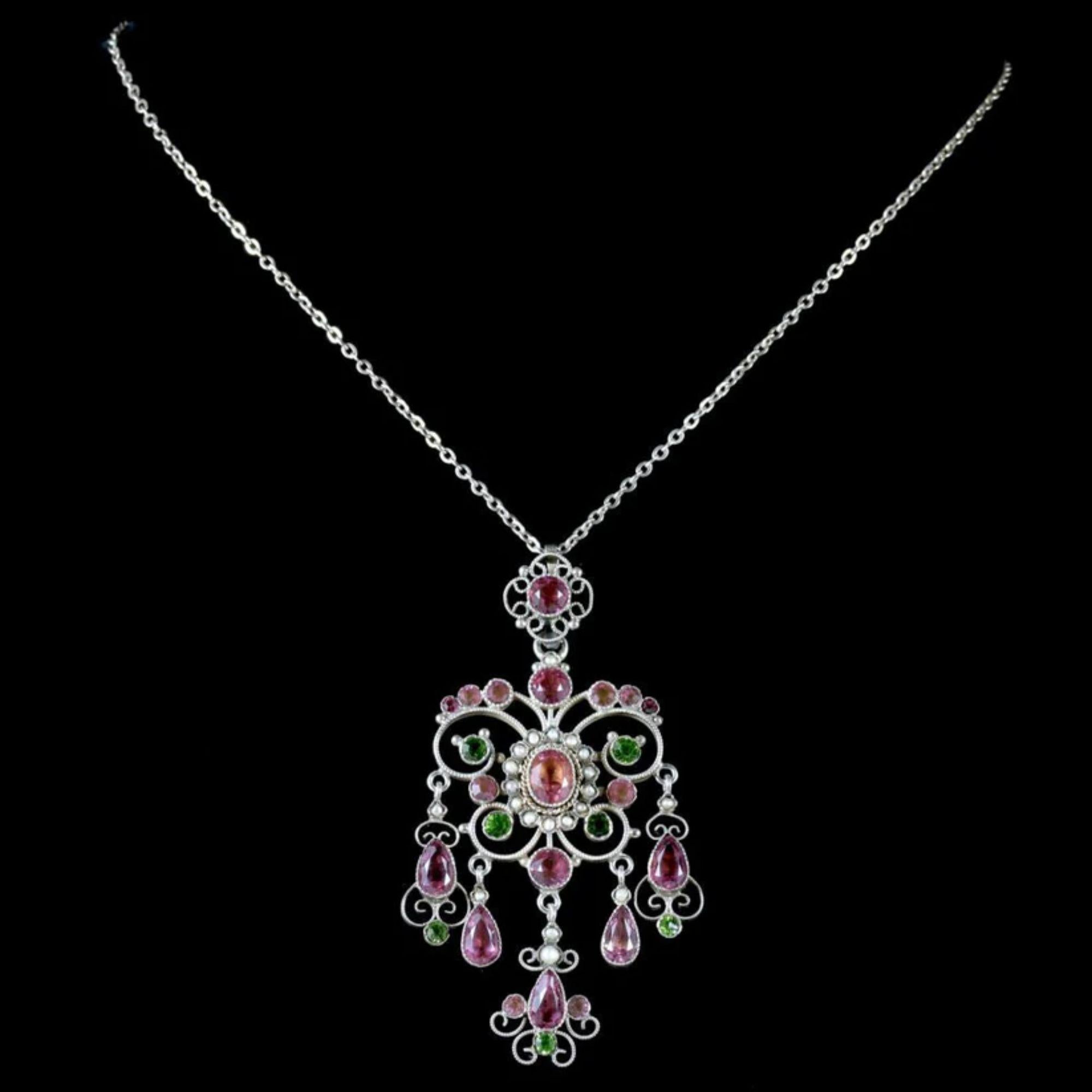 A colourful antique Edwardian pendant made in support of the women’s Suffrage movement in the early 20th Century. The silver pendant has an elaborate, open-work design with scrolling motifs and five long droppers hanging from the bottom.

It’s