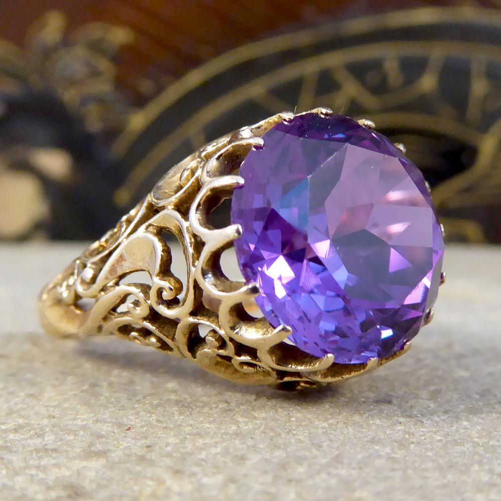 Such lovely detailed craftsmanship has gone into this ring and moulded from 14ct yellow Gold. Its been created in the Edwardian era and features a large Synthetic Alexandrite stone showing bright blues and deep purples depending on the light. 

Ring