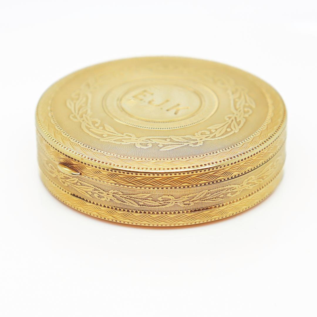 A fine Edwardian pill box or compact.

By Tiffany & Co.

In 14k yellow gold.

With engine-turned decoration throughout and a block letter monogram to the front.

Fixed with a bail to the top to allow to be suspended as a pendant or on a chain and