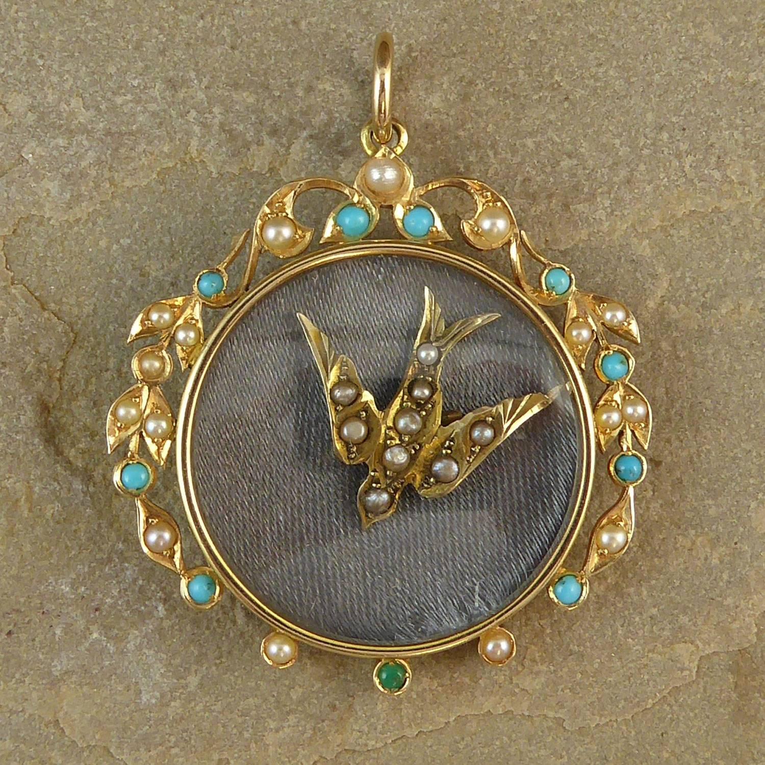 An antique pendant being a 15ct gold circular picture locket with a garland surround of turquoise and pearl in bead settings and collar mounts.  We have added an antique charm of a 9ct gold and pearl swallow, the age-old symbol of the promise to