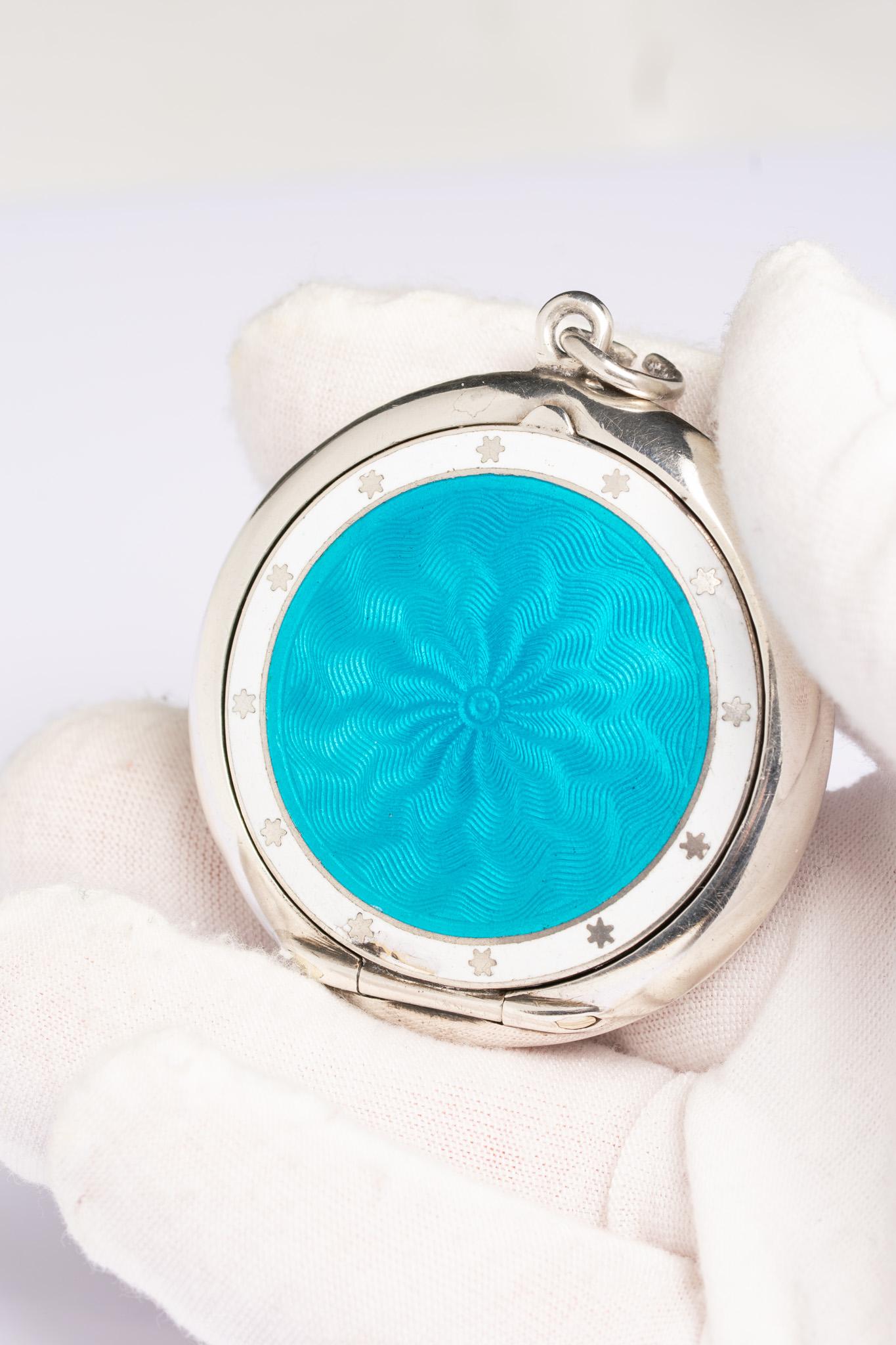 Uno straordinario e raro medaglione ovale in argento e smalto turchese guilloché di epoca edoardiana. Questo splendido pezzo è realizzato con un sorprendente e vibrante smalto arabescato turchese e bianco con un motivo a stella in argento intorno al