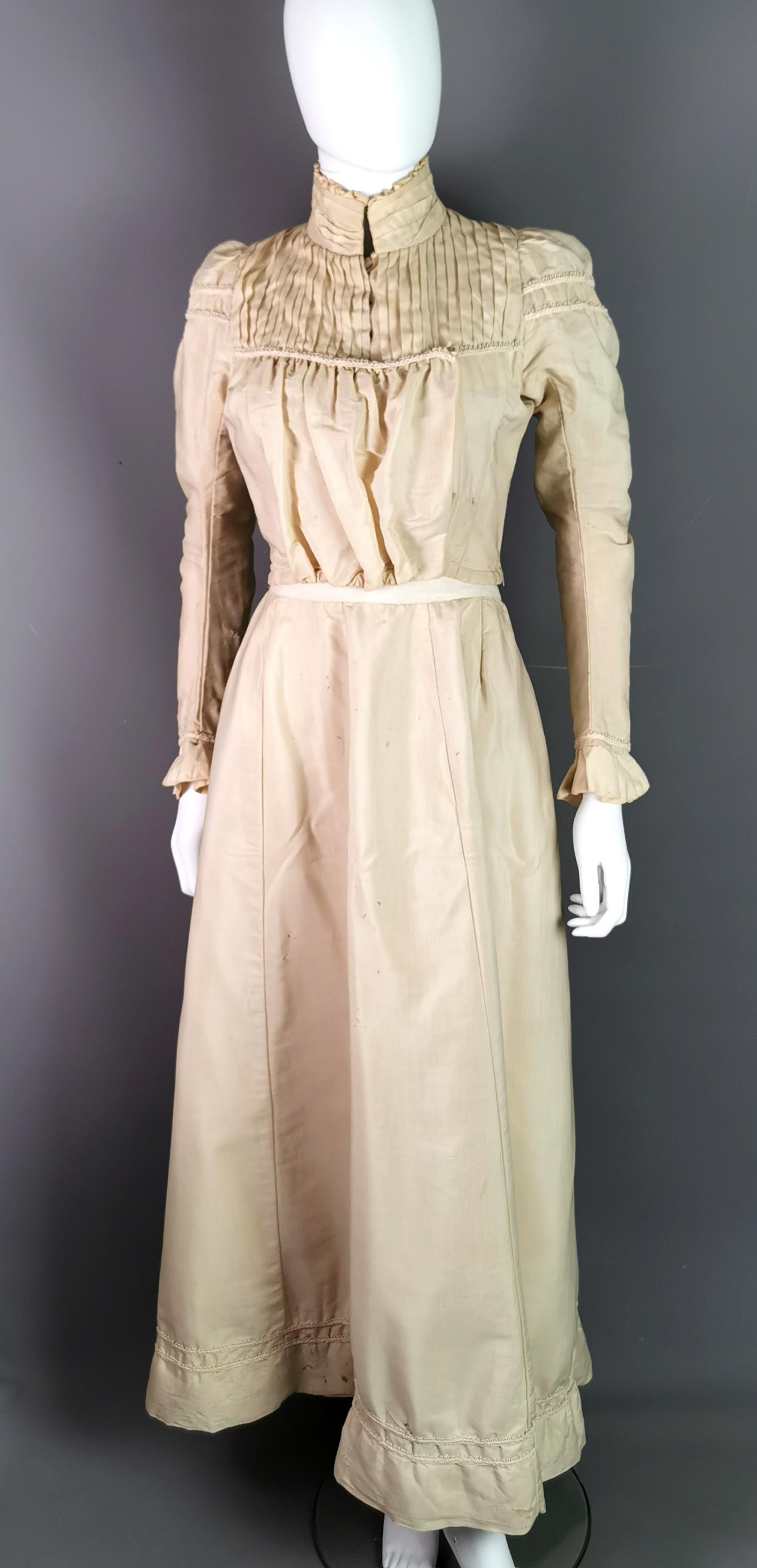 A rare antique early Edwardian day dress.

A two piece dress comprising of a pigeon chest Pouter bodice or blouse with long sleeves and flared cuffs, the bodice fastens across with hook and eye fasteners, it has a high neck with a ruffled collar and