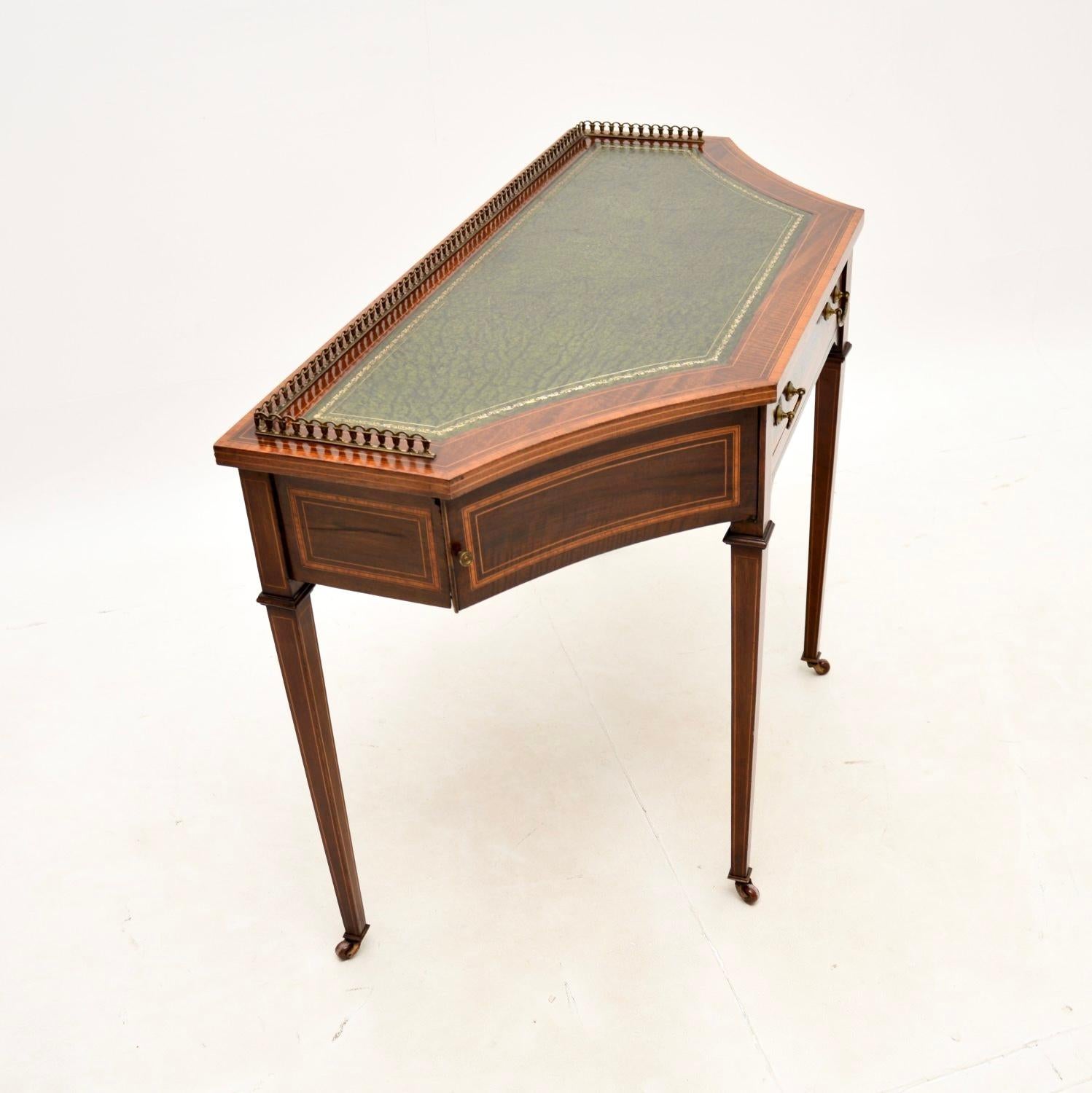 A wonderful antique Edwardian inlaid writing table / desk. This was made in England, it dates from the 1900-1910 period.

It has a fantastic design and is of superb quality. The break fronted top has a pierced brass gallery, it stands on tapered
