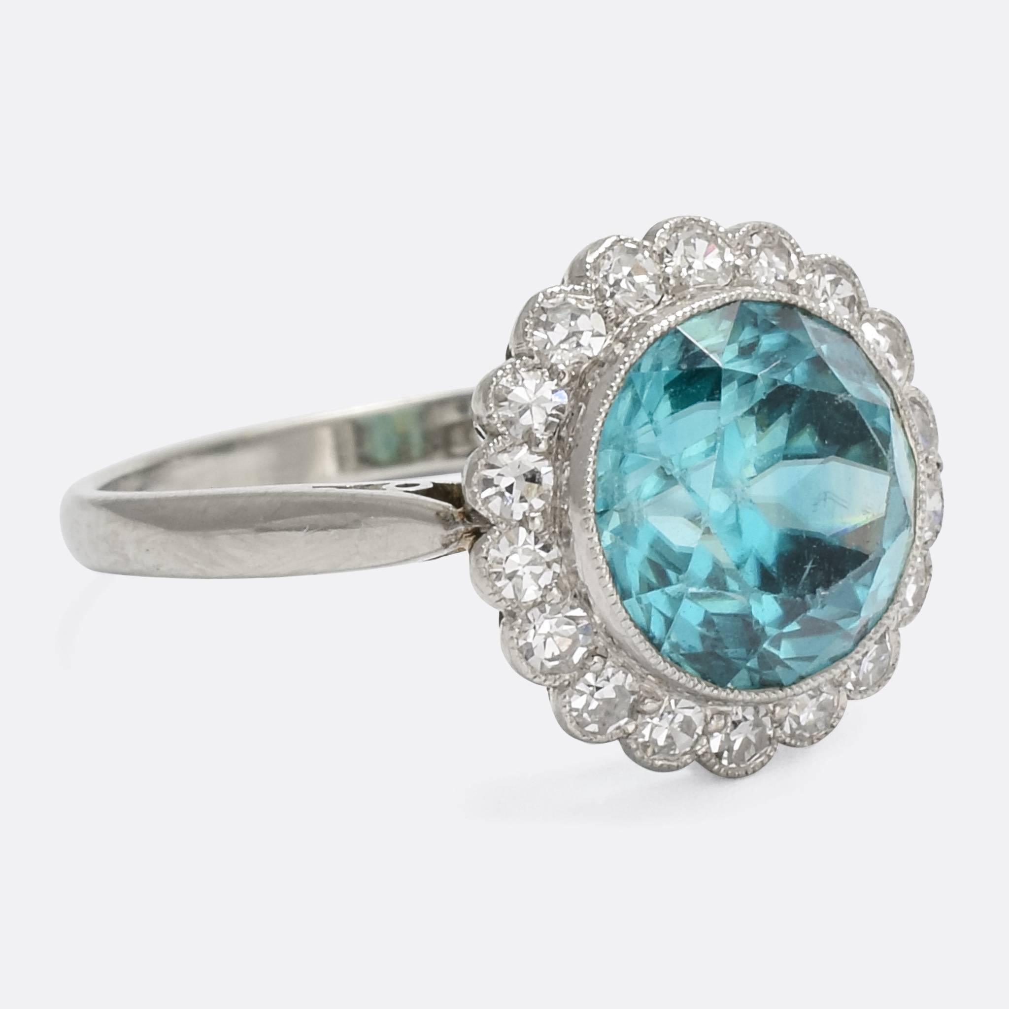 A particularly lovely antique flower cluster ring, set with a stunning blue Zircon within a halo of white Diamonds. The stones rest in fine millegrain platinum settings, with each diamond set in its own individual 