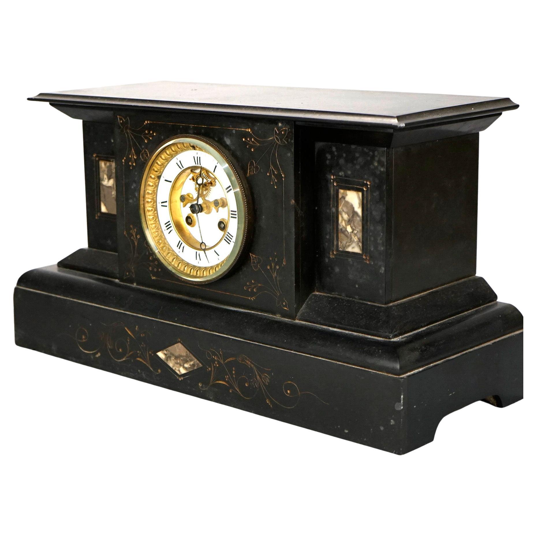 An antique Egyptian Revival garniture set offers slate mantel clock with inset marble, incised and gilt foliate decoration and flanking urn form stands, 19th century

Measures- Stands 9.5''H x 5.25''W x 4.25''D; Clock 9.5''H x 17.5''W x 7''D
