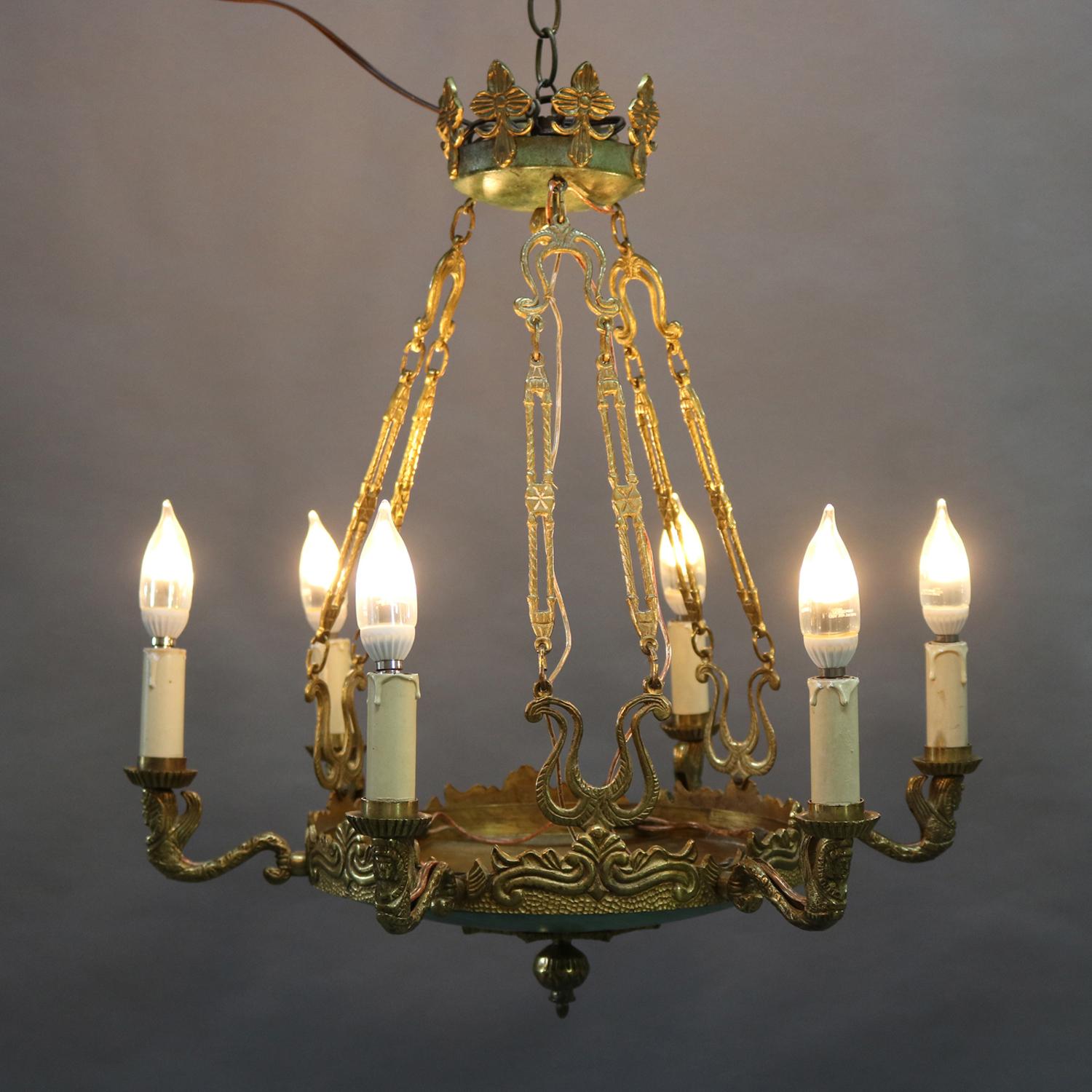 Antique Egyptian Revival chandelier features brass and bronzed metal scroll and foliate form frame with central faux marble painted bowl having central drop finial and six figural S-scroll arms terminating in sphinx masks each supporting drip candle