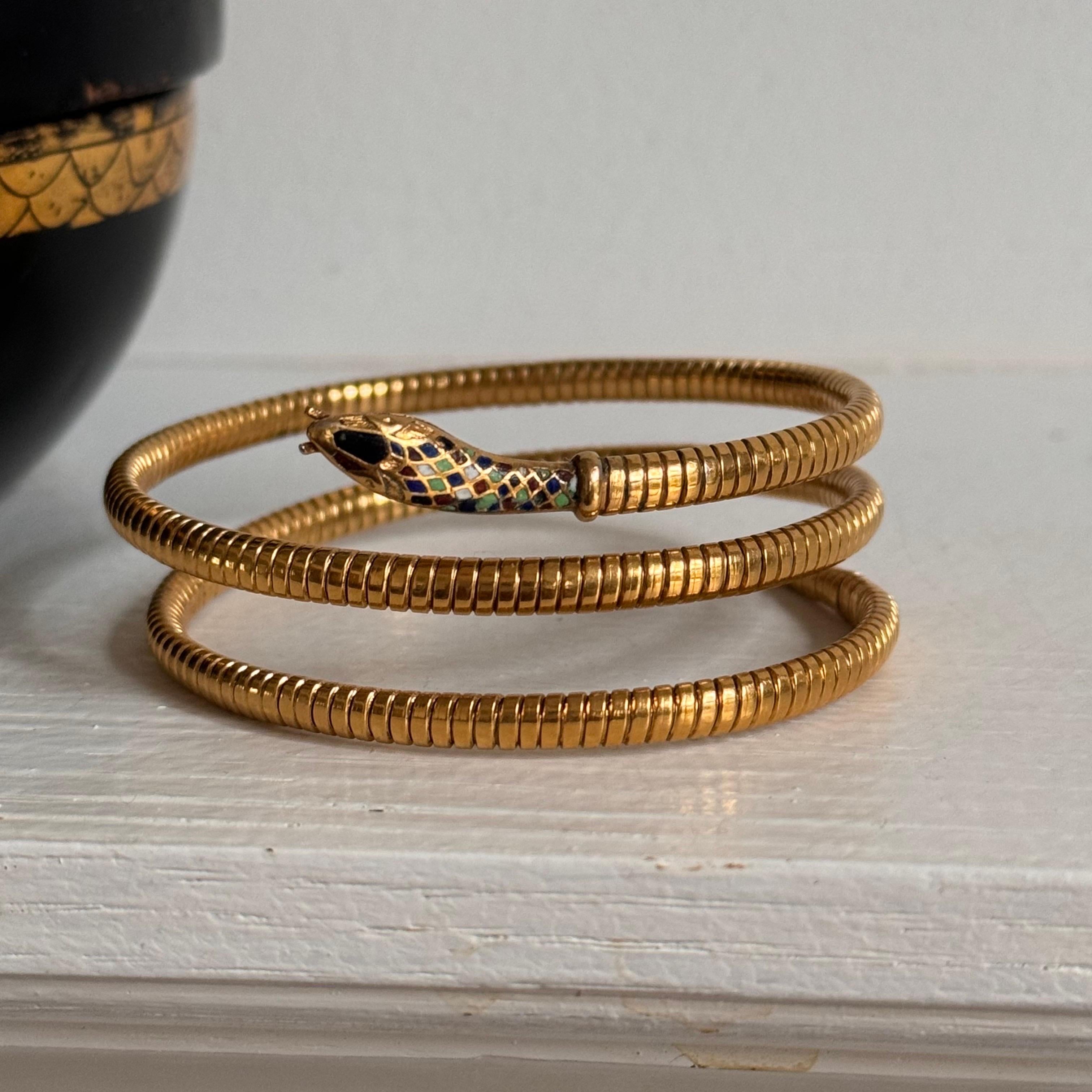 Questo squisito braccialetto antico combina magnificamente l'opulenza dell'epoca Art Deco con il misticismo del periodo della rinascita egizia. Realizzato in metallo riempito d'oro, il braccialetto presenta un design a serpente arrotolato, con il