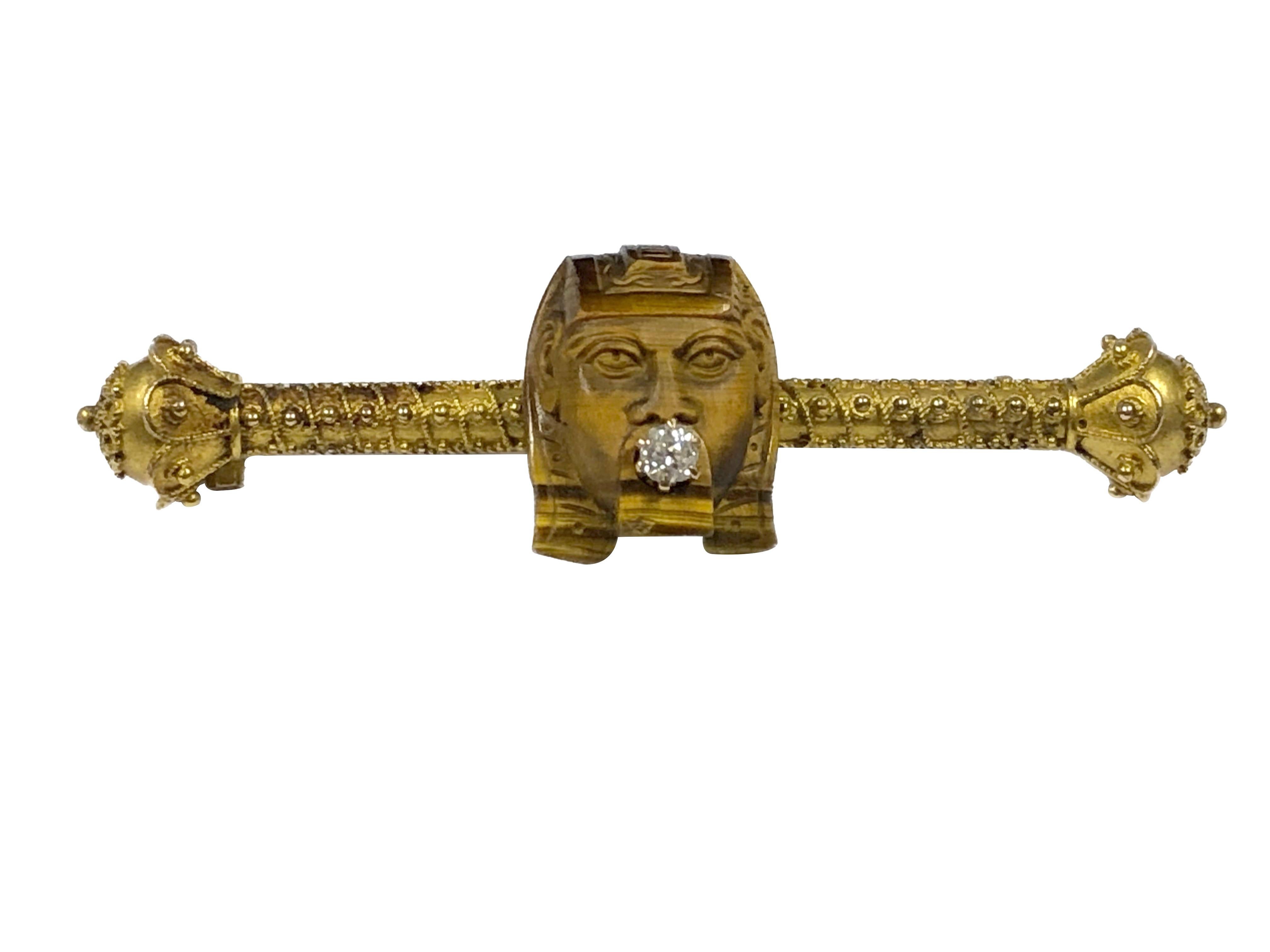 Circa 1880 - 1890 14K Yellow Gold, Egyptian Revival Brooch, measuring 2 1/4 inches in length and having fine Etuskan Granulation work, centered by a Carved Tigers eye stone Sphinx with an old mine cut Diamond set into the Mouth. 