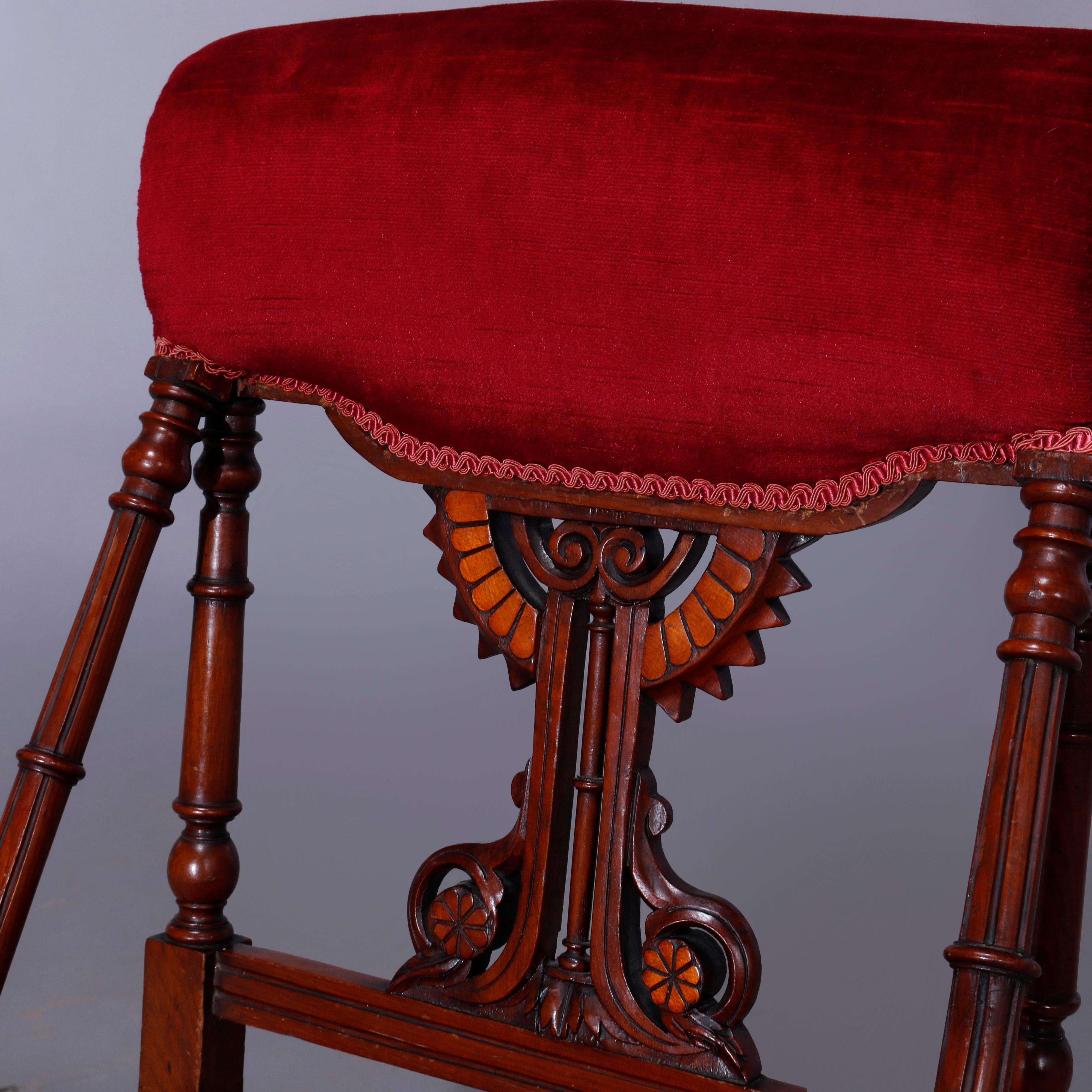 An antique Egyptian Revival slipper chair in the manner of Kimble & Cabus offers walnut frame with upholstered scroll form rail over open back with carved stylized sunburst and floral elements terminating in upholstered seat, c1870

Measures - 31''