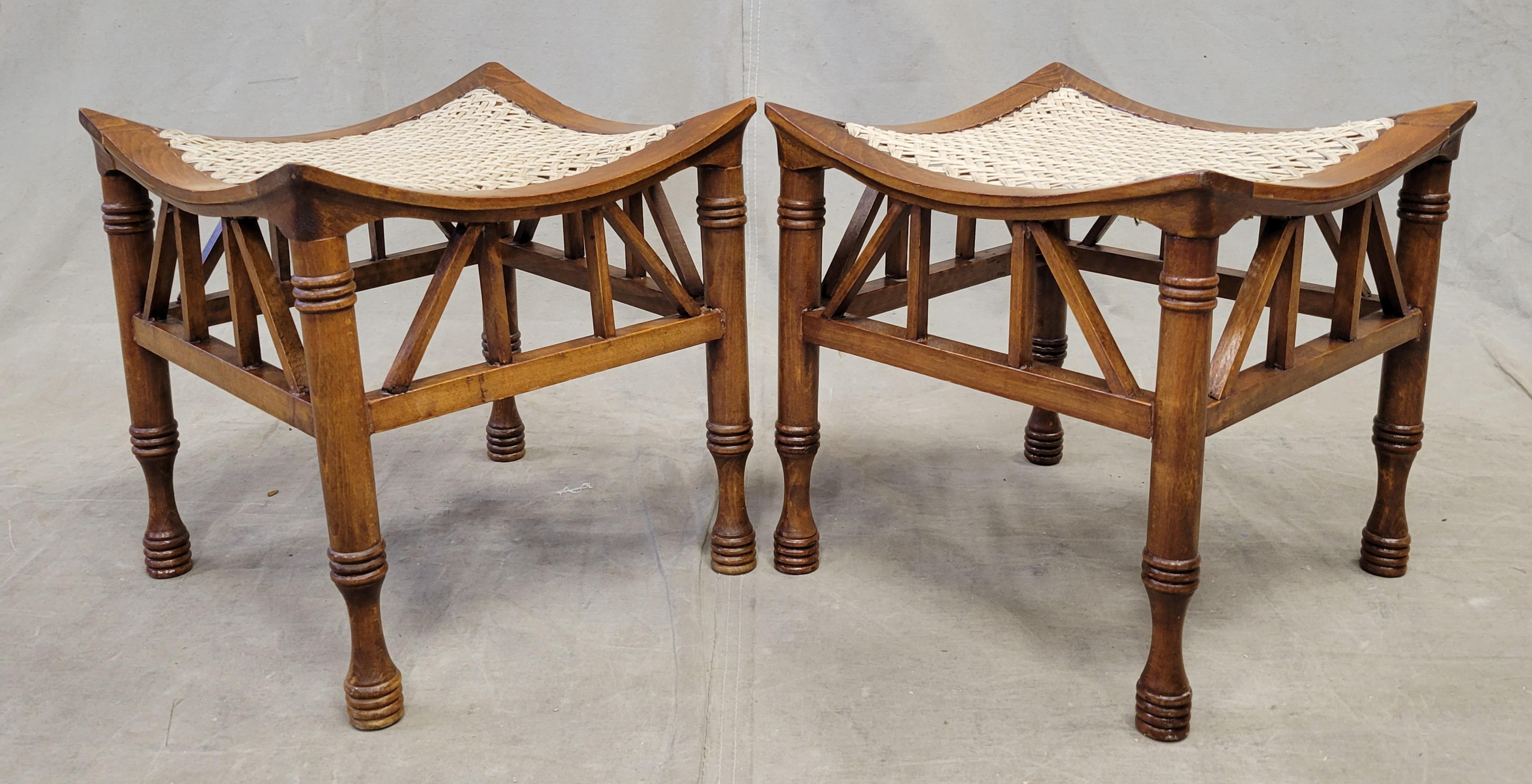 This charming pair of Egyptian Revival Thebes stools are attributed to Liberty & Co. of London. This style of stool was manufactured in England from 1884-1919 as part of the popular Egyptian revival design style. Made of stained pine or beech wood