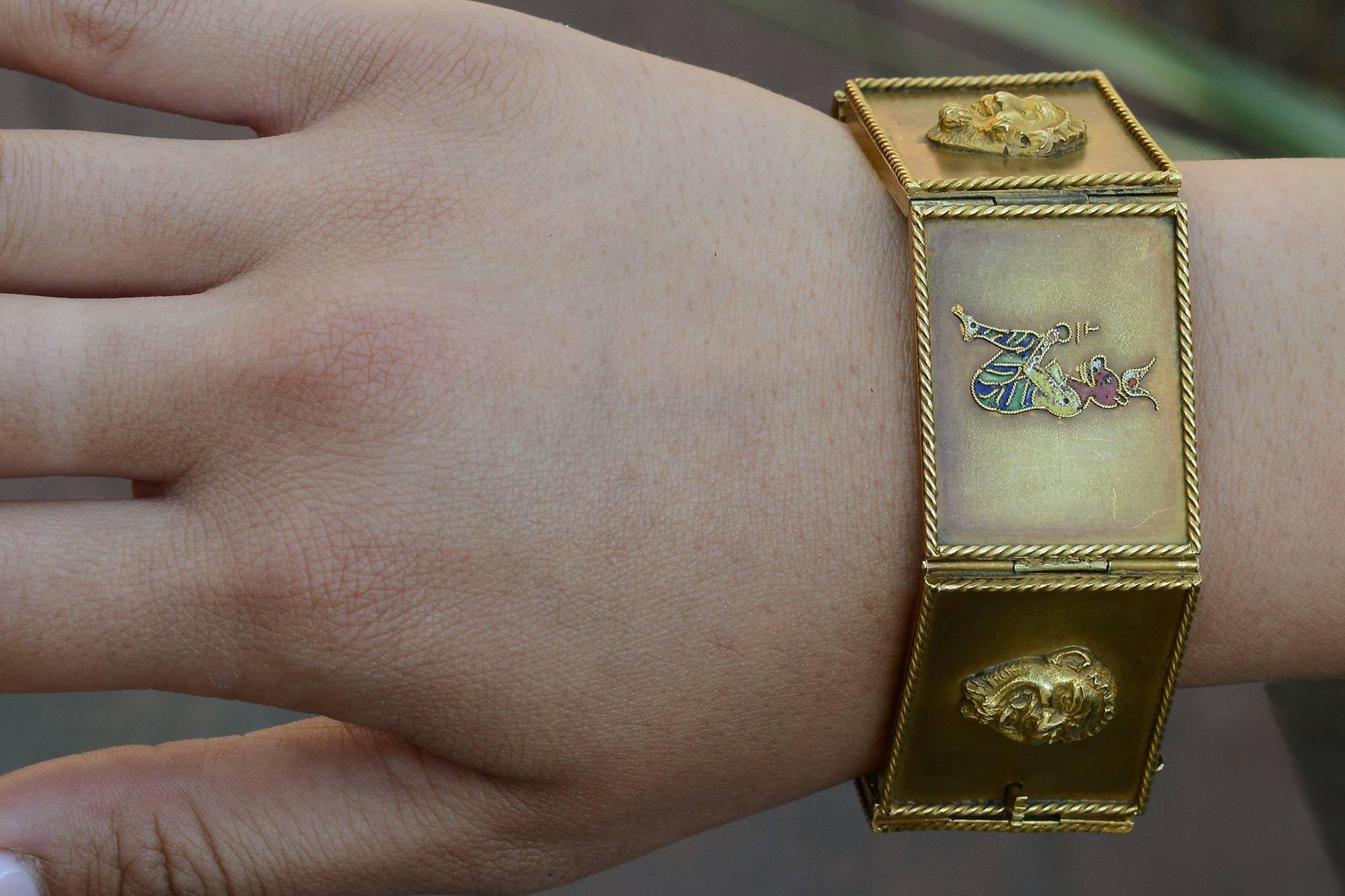 A fascinating Egyptian revival bracelet from the turn of the century. Each link an individual rope-framed panel featuring faces of Greek heads, with enamel eastern Buddhist and Egyptian figures depicting a story of some type. Hand crafted of 18kt