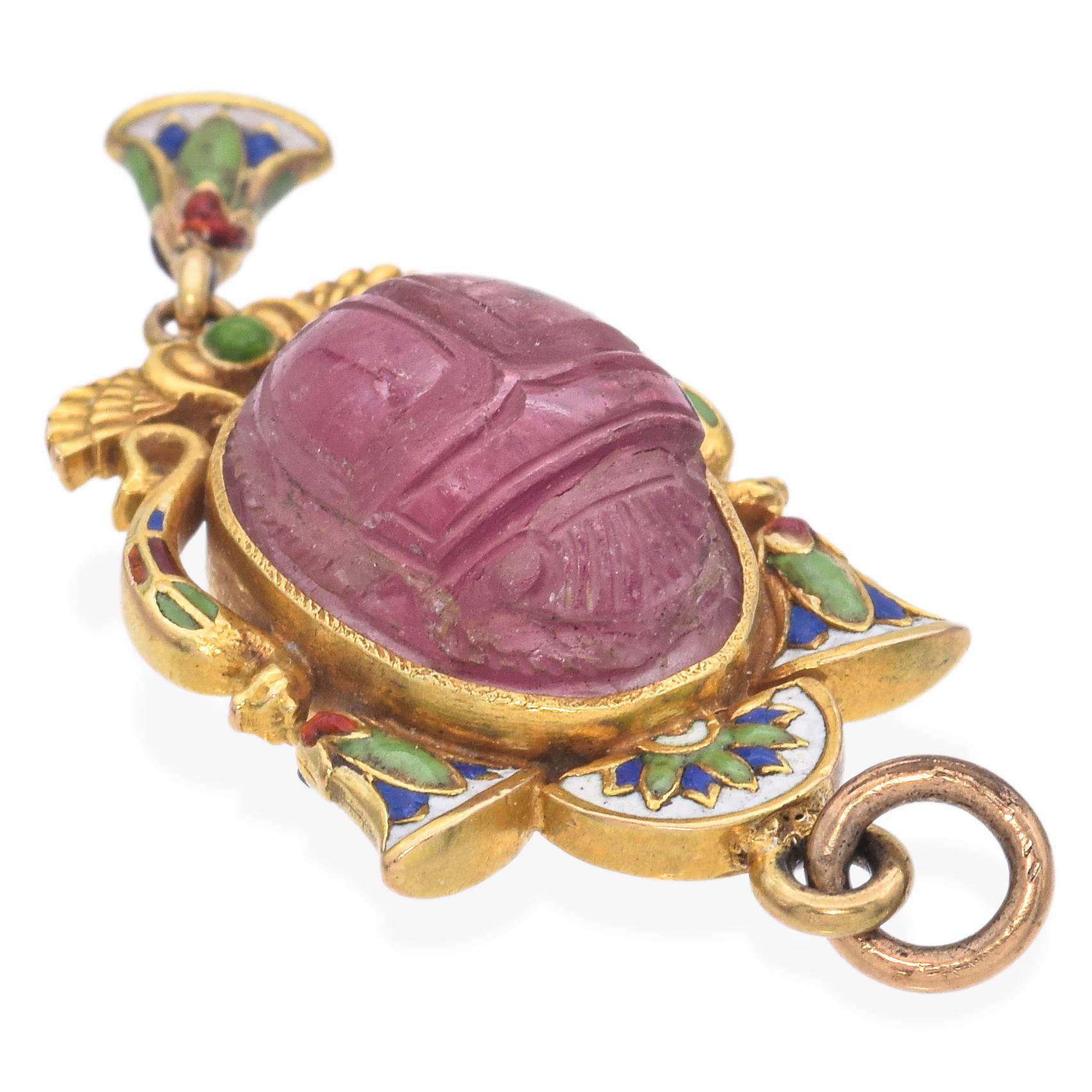 Explore the intricate beauty of this pendant. Crafted in yellow gold, the pendant showcases a carved pink tourmaline scarab, framed by colorful enamel motifs.

Weight: 6.3 Grams 
Stone: Pink Tourmaline (13.5 x 10 x 6.25 mm) 
Measurements: 39 x 17.2