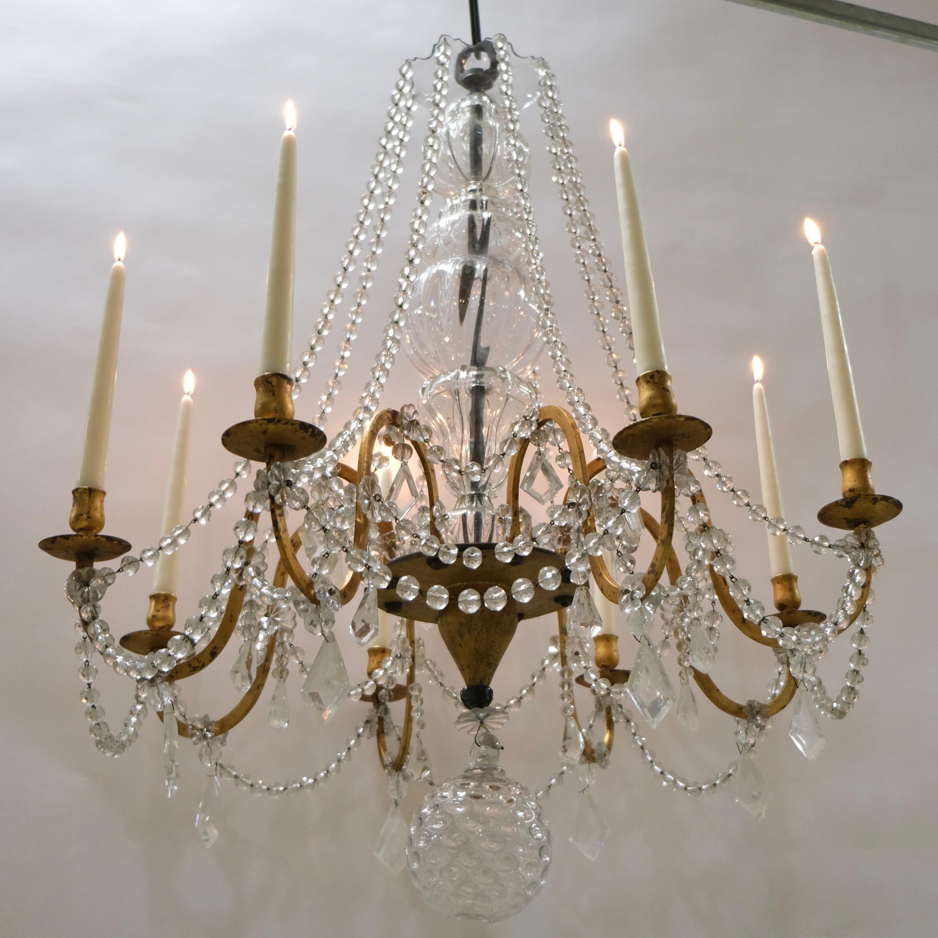 Questo lampadario antico con otto bracci e candelabri ha proporzioni fantastiche e una sensazione davvero genuina. Una spessa vasca in ferro forgiato è lo stelo centrale del lampadario. È ricoperto di cristallo soffiato a mano che gli conferisce una