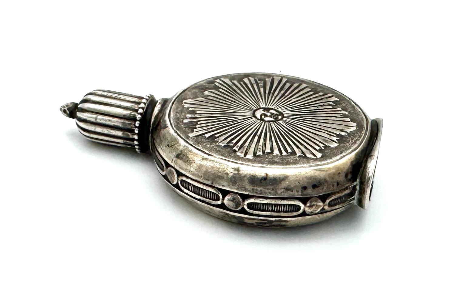 This unusual miniature silver scent bottle was created towards the end of the 19th century. On both sides of the bottle we see a large sun with a face, the sun rays spreading over the entire surface on each side. The side of the bottle is decorated
