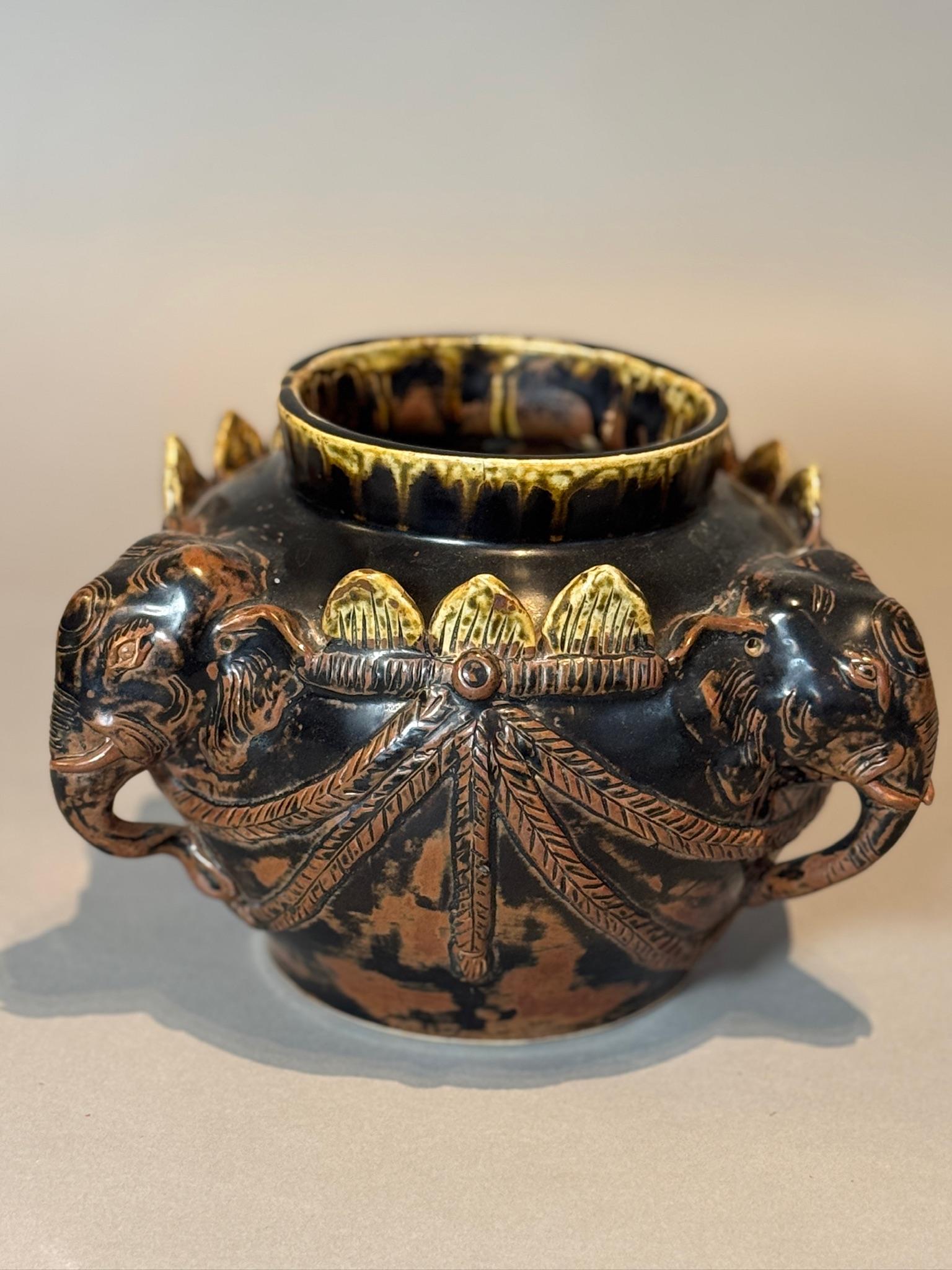 Ce superbe récipient antique en céramique est un chef-d'œuvre d'artisanat. Il présente un motif d'éléphant sculpté très élaboré qui respire l'élégance et la signification culturelle. Probablement inspirée par les designs traditionnels asiatiques ou