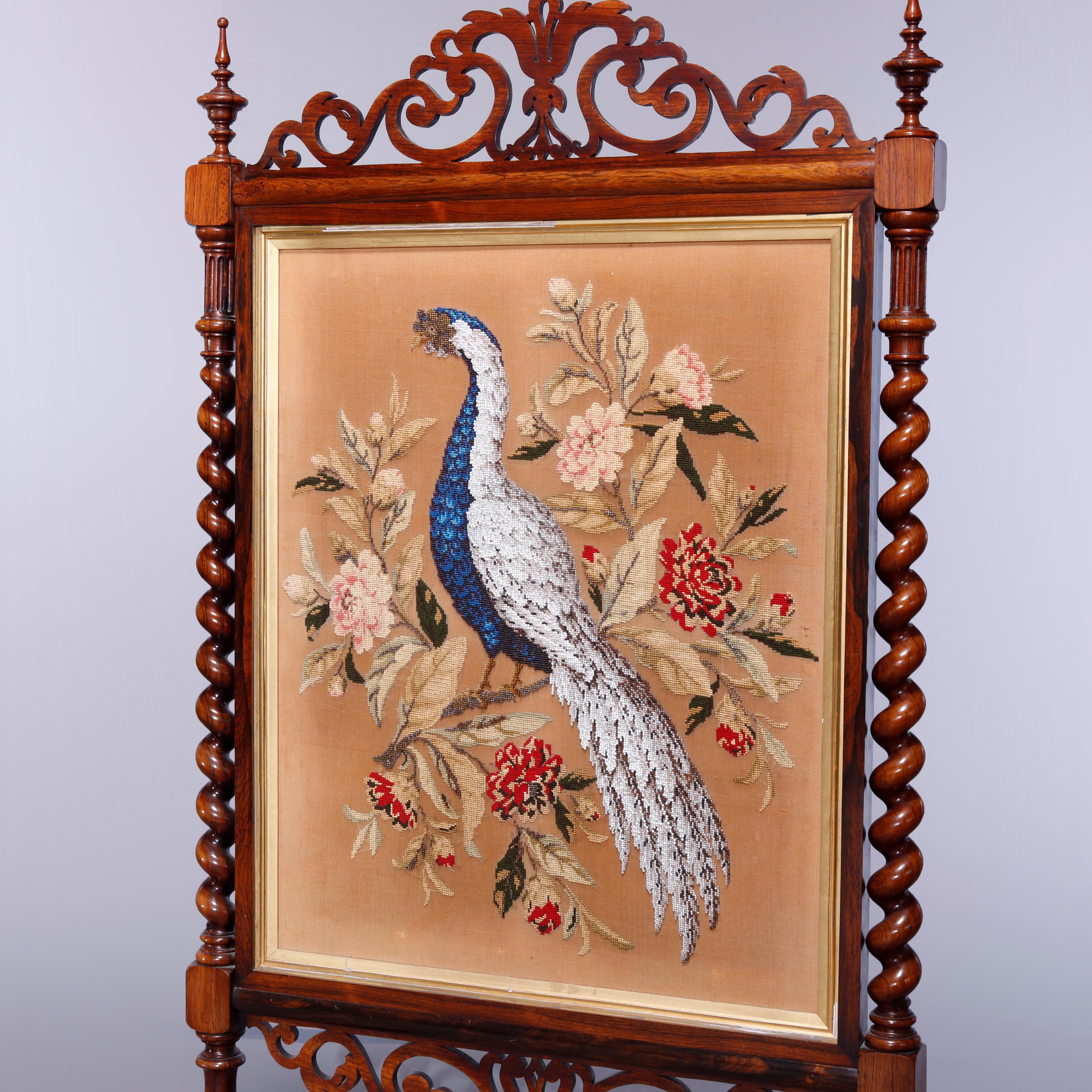 An antique Elizabethan fire screen offers carved frame with scroll filigree crest having flanking turned finials and rope twist frame with central needle and beadwork panel with garden scene having peacock, raised on cabriole legs,