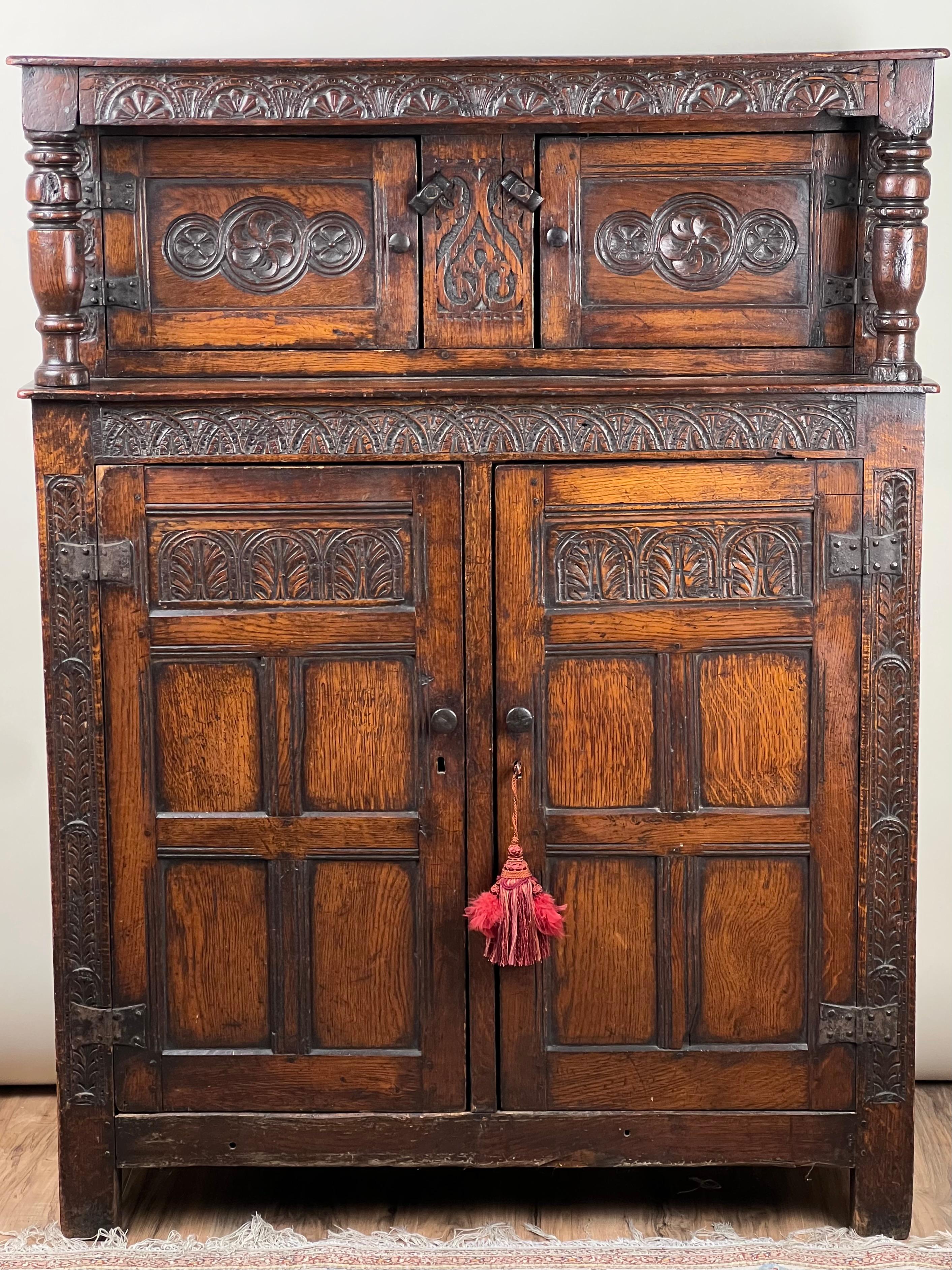 Cette ancienne armoire de cour en chêne Tudor élisabéthain, datant de la fin du XVIe siècle, illustre l'artisanat et les valeurs esthétiques de la période Tudor. Construite en chêne richement grainé, cette armoire présente des sculptures profondes
