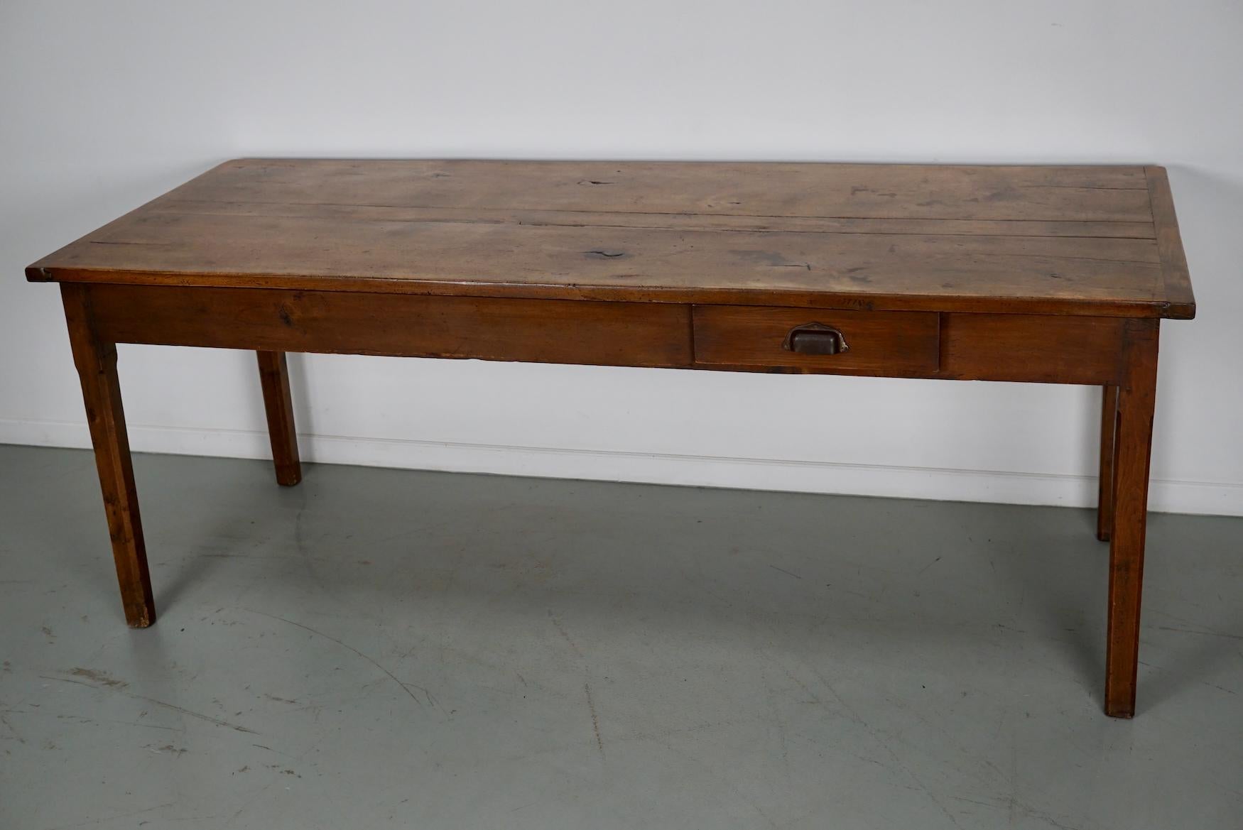 Cette élégante table a été fabriquée en France au XIXe siècle. Le plateau de la table est en orme avec de magnifiques veinures. La couleur est très chaude et la table présente de nombreuses marques d'utilisation, d'anciennes réparations et une belle