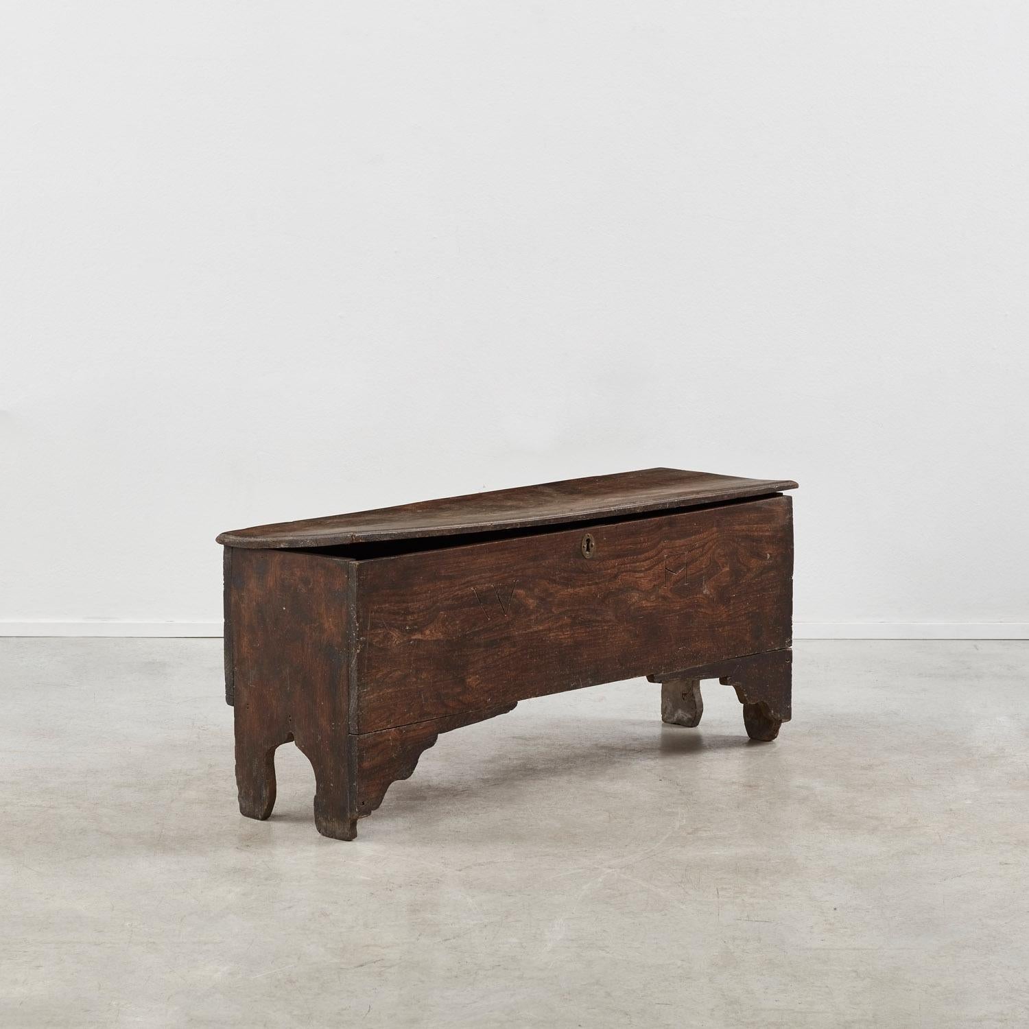 Le venature storiche del legno definiscono questo forziere in olmo del XVII secolo. Caratterizzata da una lavorazione curvilinea e da dettagli apogei ai piedi, questa cassapanca antica è completata da un piccolo cassetto interno e da un coperchio.