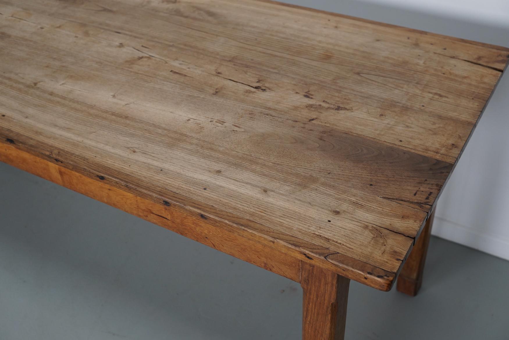 Cette table élégante a été fabriquée dans le sud de la France au début du 20e siècle. La table a été fabriquée en orme massif avec de magnifiques veinures. Elle a une couleur claire très chaude et la table présente de nombreuses marques