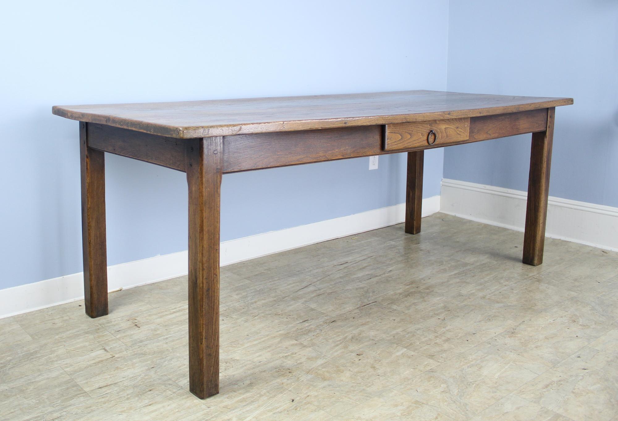 A handsome elm dining table or farm table with handsome straight legs and a single drawer at the side. The top has lovely color, grain and patina. 24 inch apron height is good for knees and there are 67.5 inches between the legs on the long side.