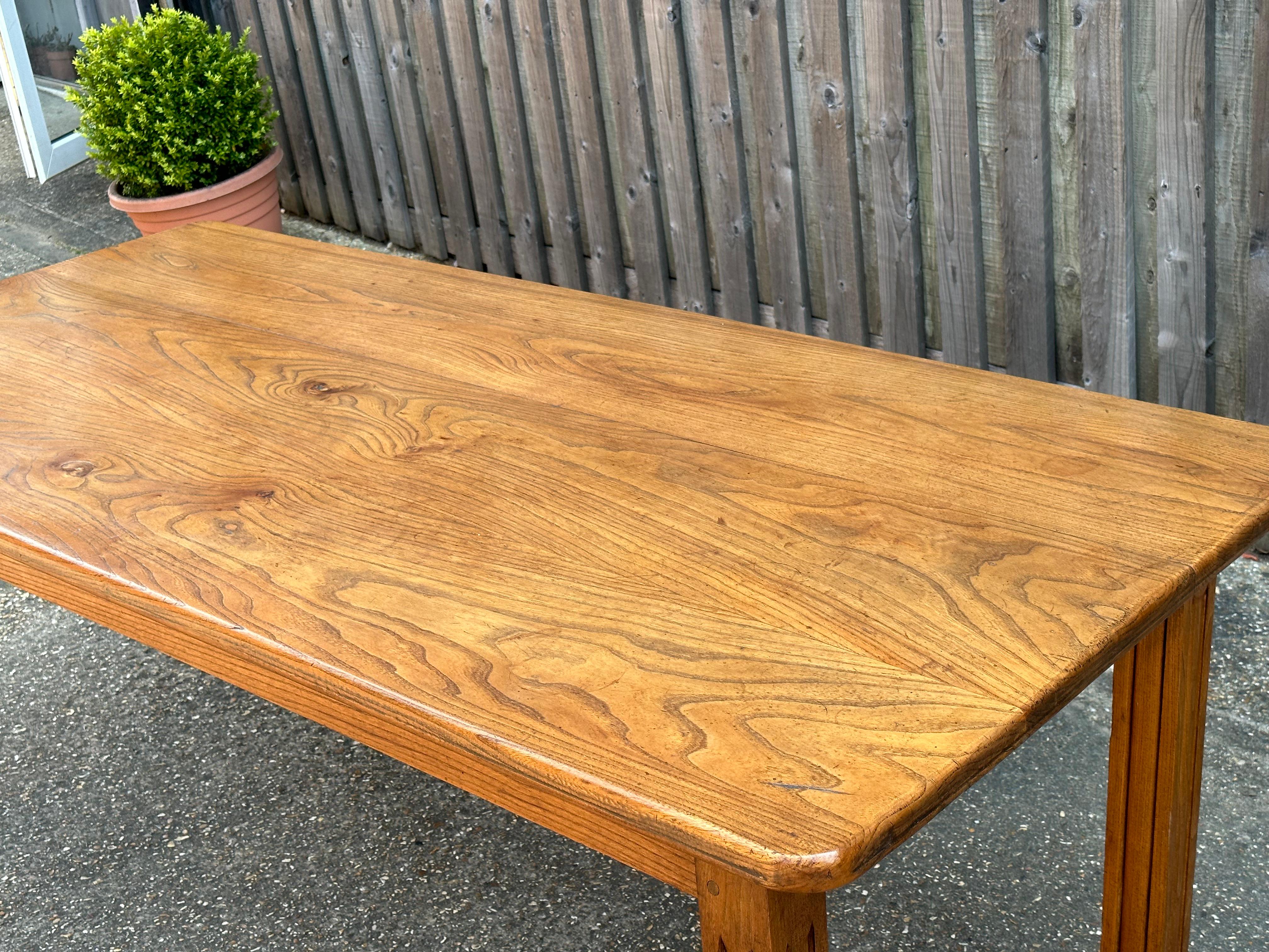 Early 20th Century elm, three plank table top. The top has stunning patination and figured grain. The table sits on a sturdy apron with four square carved legs. The table is a perfect eight-seater and would work well in a kitchen or dining room. The