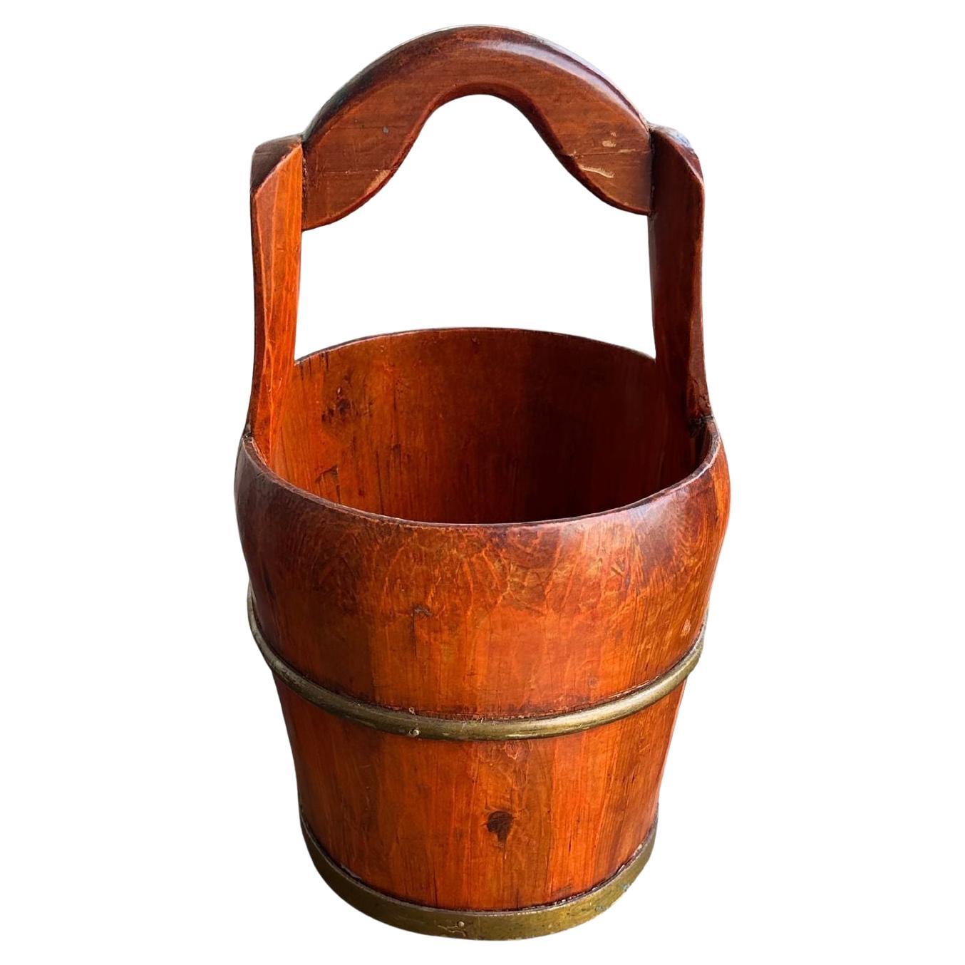 Our antique elm wood bucket, circa 1920s, a piece that combines rustic charm with historical significance. Originating from the late Qing Dynasty in China, this bucket, crafted from solid elm wood, features a natural patina that speaks to its rich