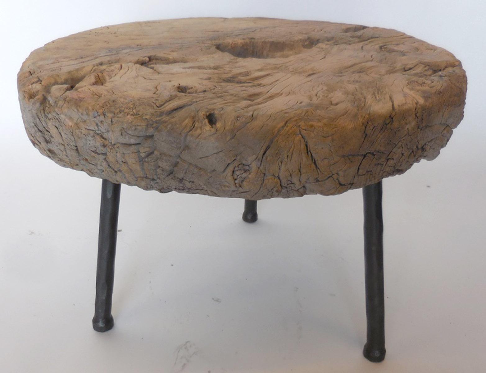 Rustic 19th century wooden elm wheel atop three contemporary hand forged iron legs. Wood shows natural patina and appropriate wear. Flat on top. Sturdy. By Dos Gallos Studio. 