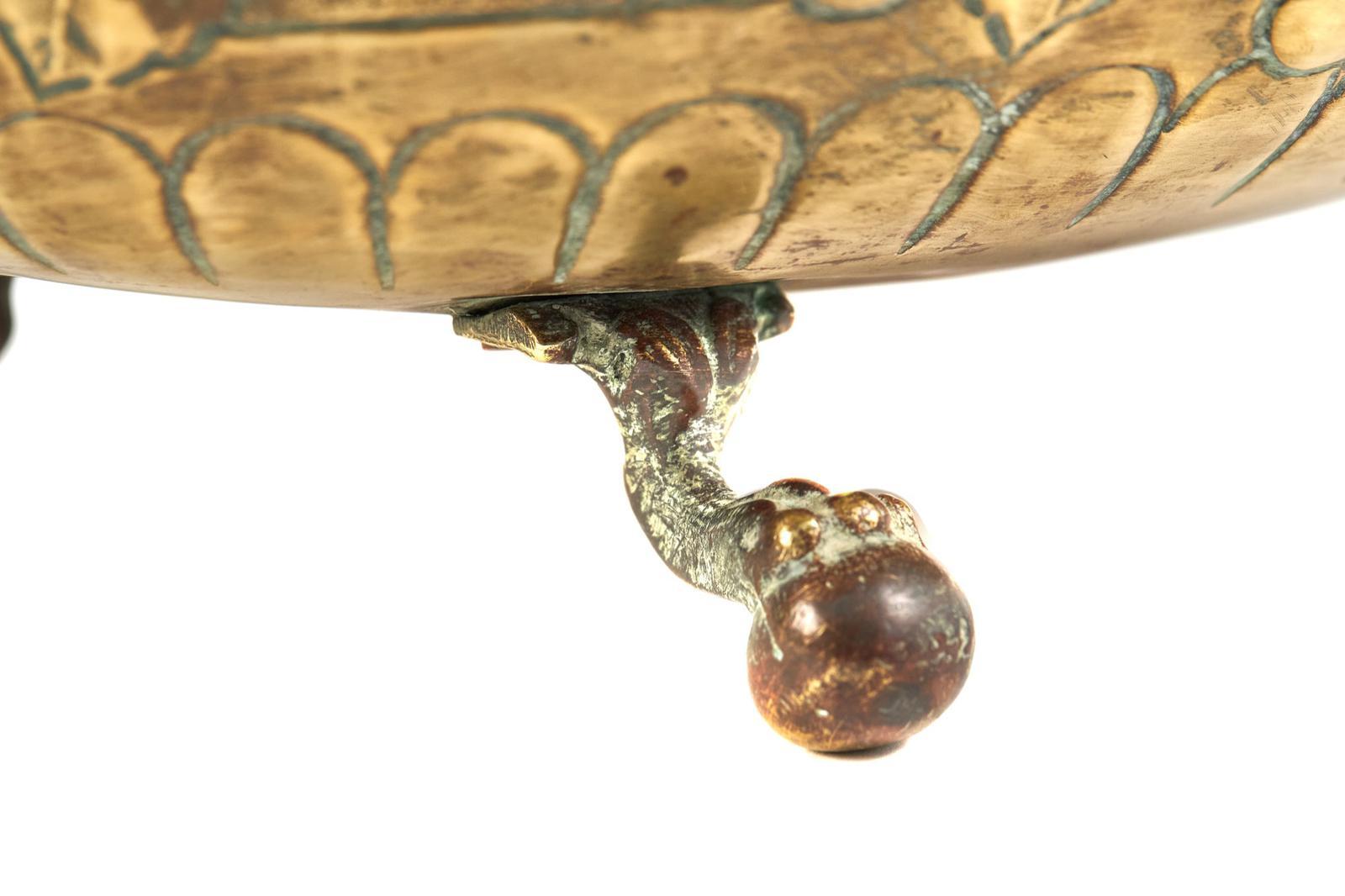 Ancienne jardinière en laiton gaufré, décorée de vignes, avec des poignées de transport en forme de masque de lion de chaque côté et reposant sur des pieds en forme de boule et de griffe.