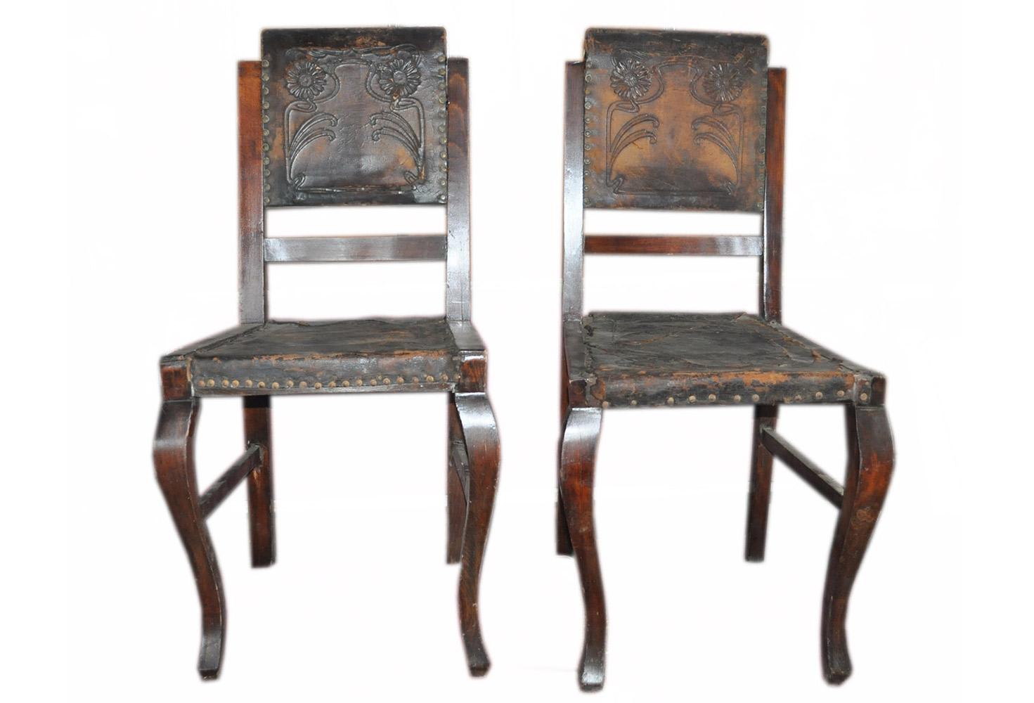 Original embossed leather upholstery. Wooden base and frame. Antique brass nailhead trim.
Set of two Hungarian brown embossed leather dining chairs. The chairs are in good conditions. 
The leather is sometimes damaged and cracked. Wooden base is