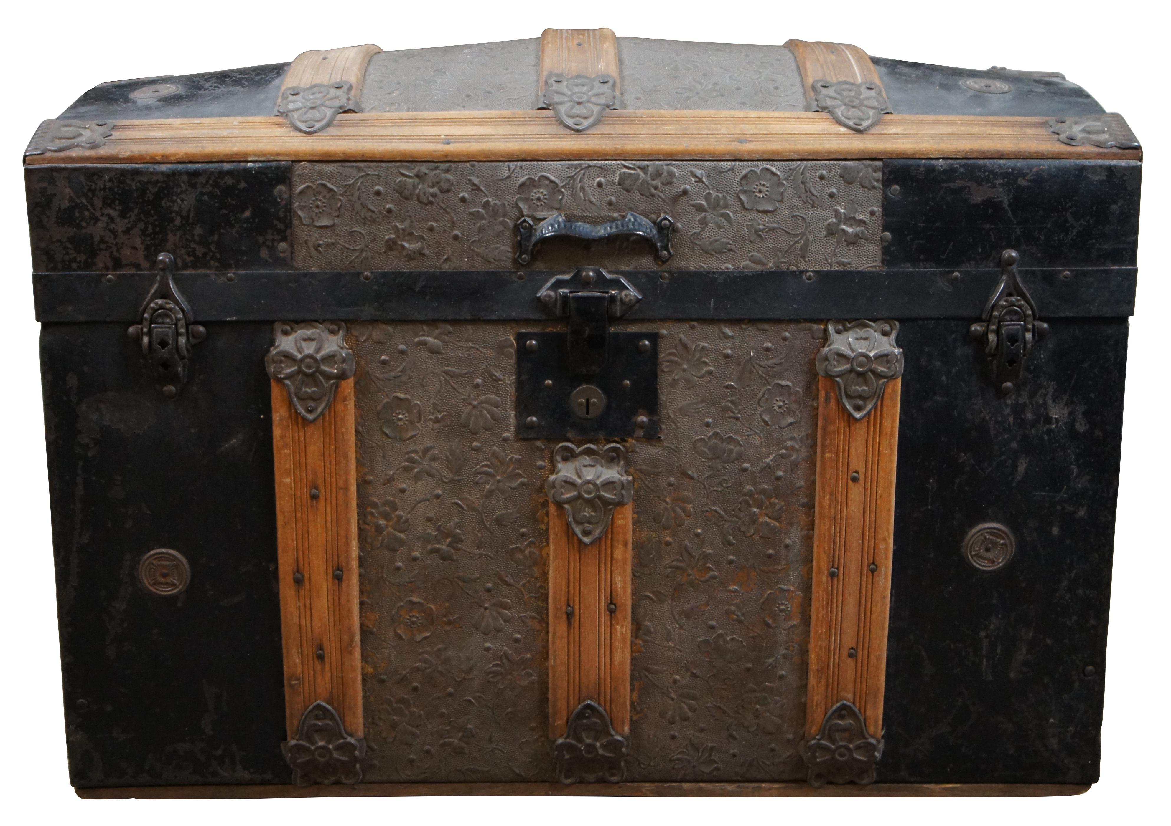 Antique Victorian era dome top / hump back style steamer trunk made of oak and metal with floral embossed metal panels, four castors on the base, containing the original cardboard / paper mache interior compartment in the lid and removable tray,