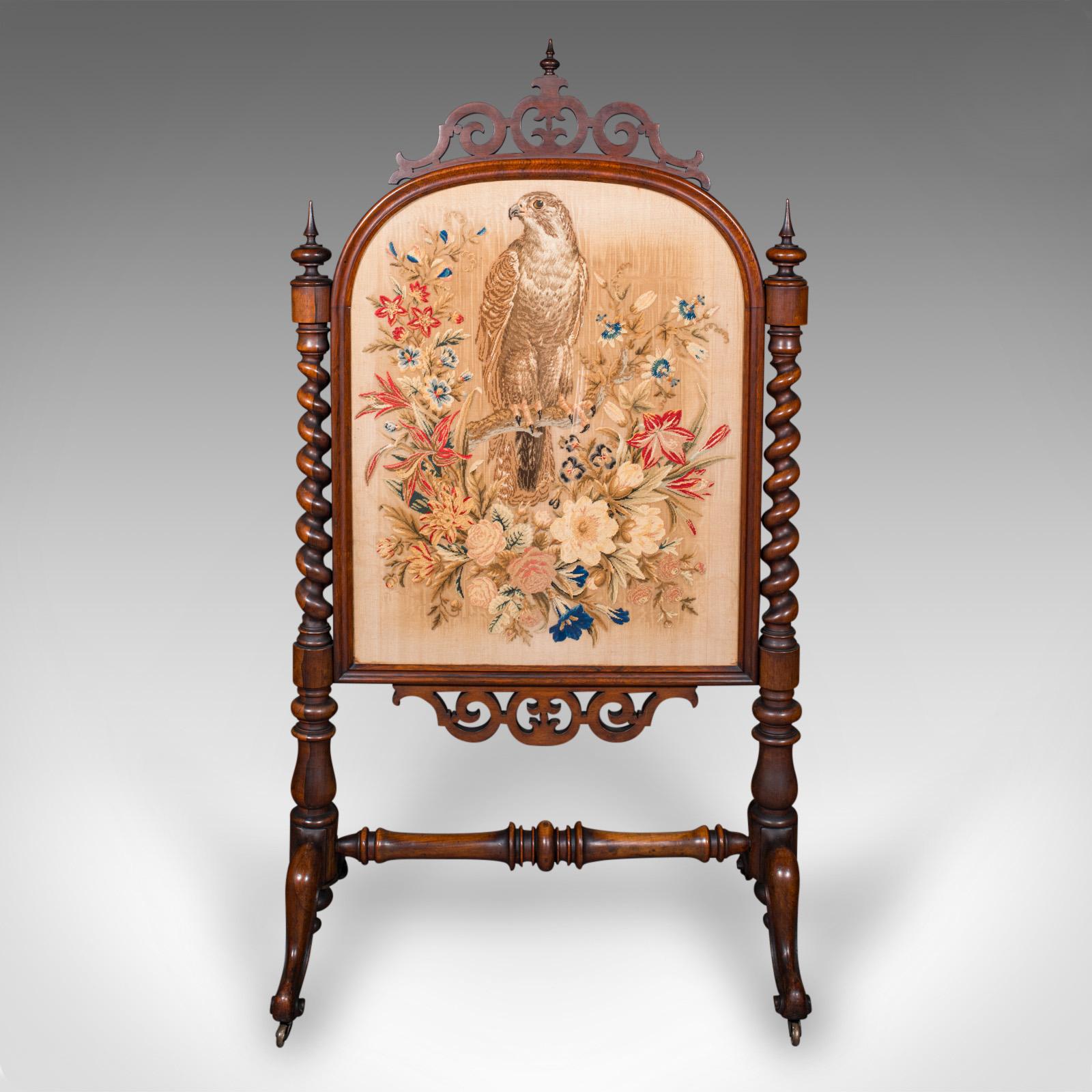 This is an antique embroidered fire screen. An English, walnut and glazed needlepoint reflector panel, dating to the early Victorian period, circa 1840. A truly exceptional example of early Victorian craftsmanship, this screen combines exquisite